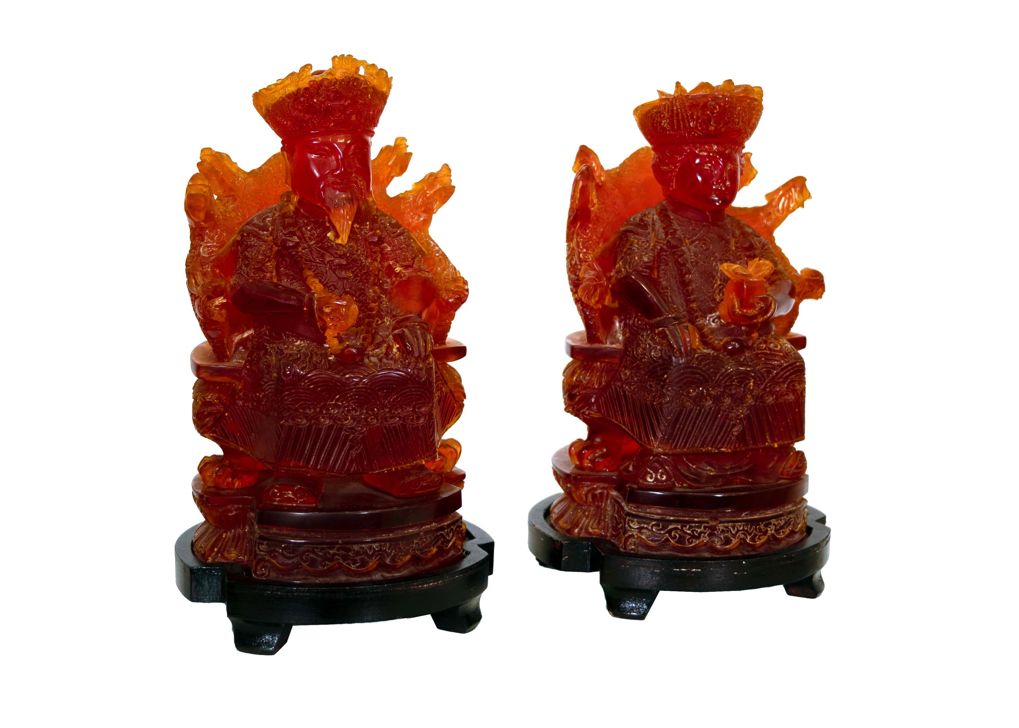 Tauchen Sie ein in die Pracht des kaiserlichen Chinas mit diesem fesselnden Paar von sitzenden Figuren, die meisterhaft aus Kirschharz gefertigt sind. Die Statuen sind mit aufwendigen Schnitzereien verziert, die die opulente Kleidung und das