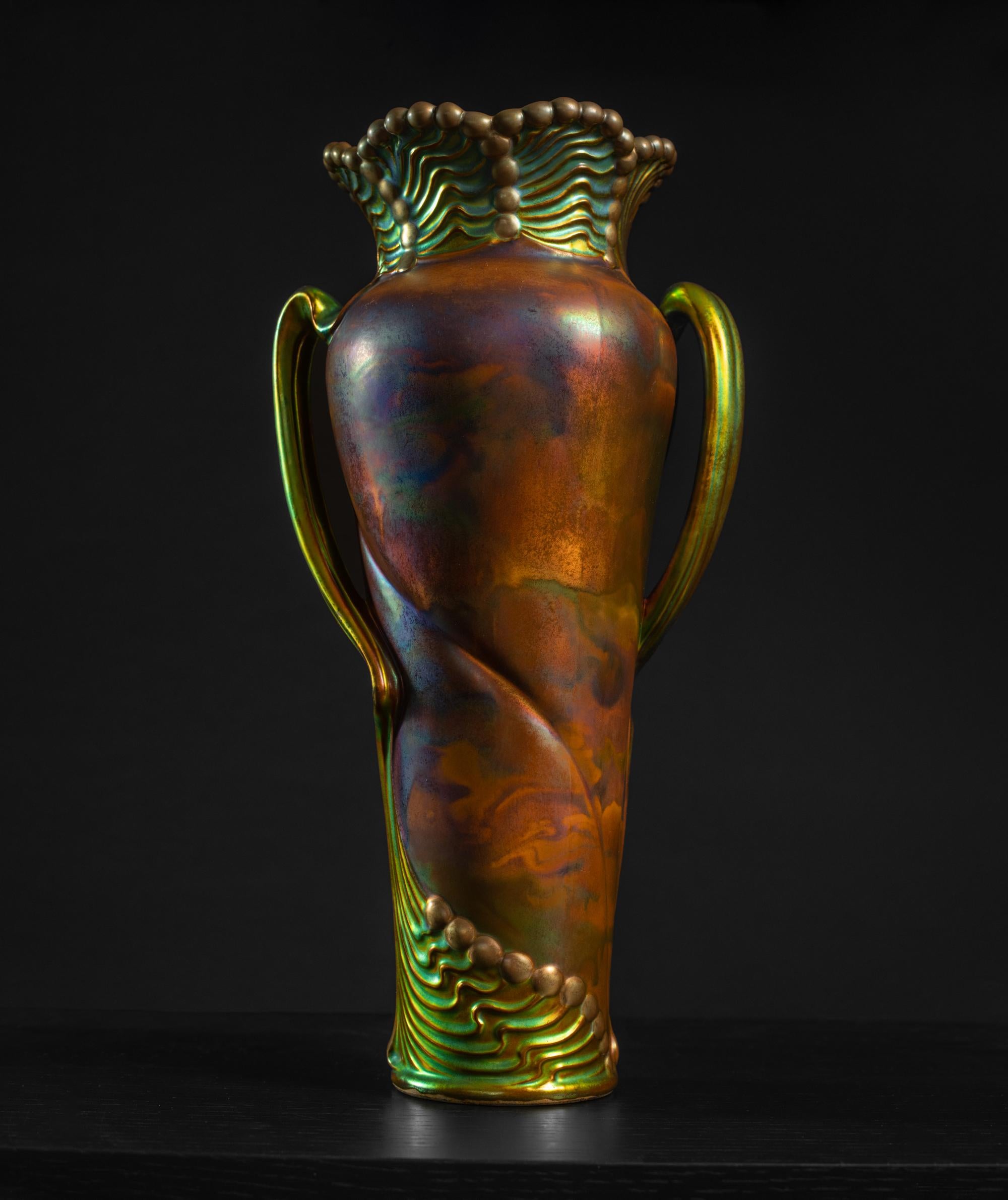 Zsolnay führte 1893 seine patentierte metallisch glänzende Glasur ein, die als Eosin bezeichnet wurde. Die kleine Familienkeramikwerkstatt, die Miklos Zsolnay 1853 in Pecs, Ungarn, gegründet hatte, hatte sich zu dieser Zeit zu einer Keramikfabrik
