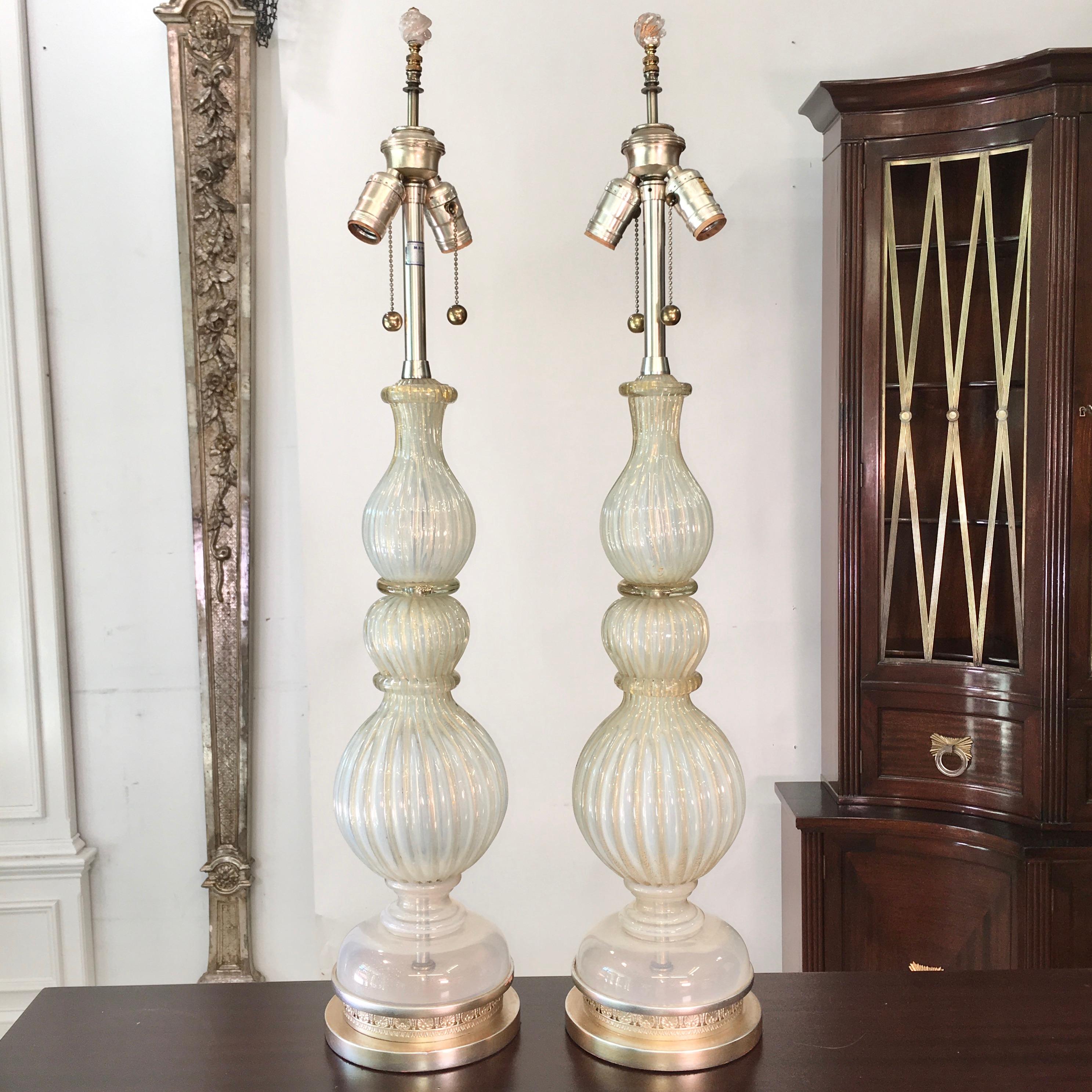 Pair of original grand scale Murano glass table lamps by Archimede Seguso imported by The Marbro Lamp Co., circa 1960. Both lamps signed.
Ribbed opalescent silvery white glass with flecks of gold. Bases have been platinum leafed with a gold