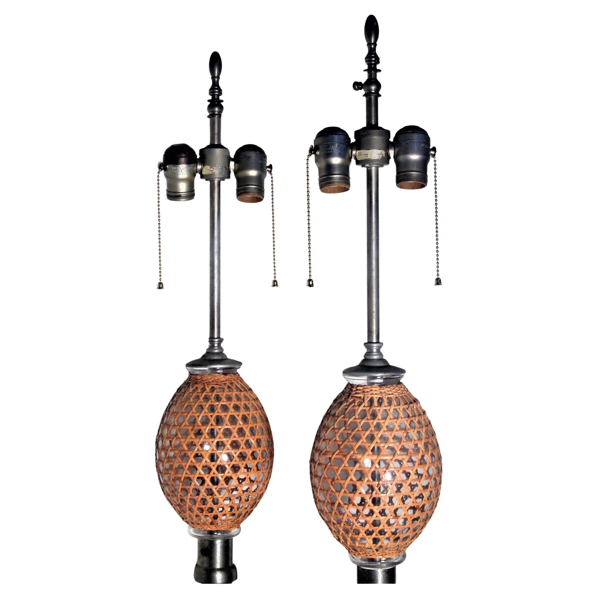 Pair of French seltzer bottle lamps each with two rattan wicker wrapped glass globes, pewter fittings and circular white porcelain bases. Overall beautifully aged original condition. Warren Kessler, New York foil labels at top of sockets. Circa