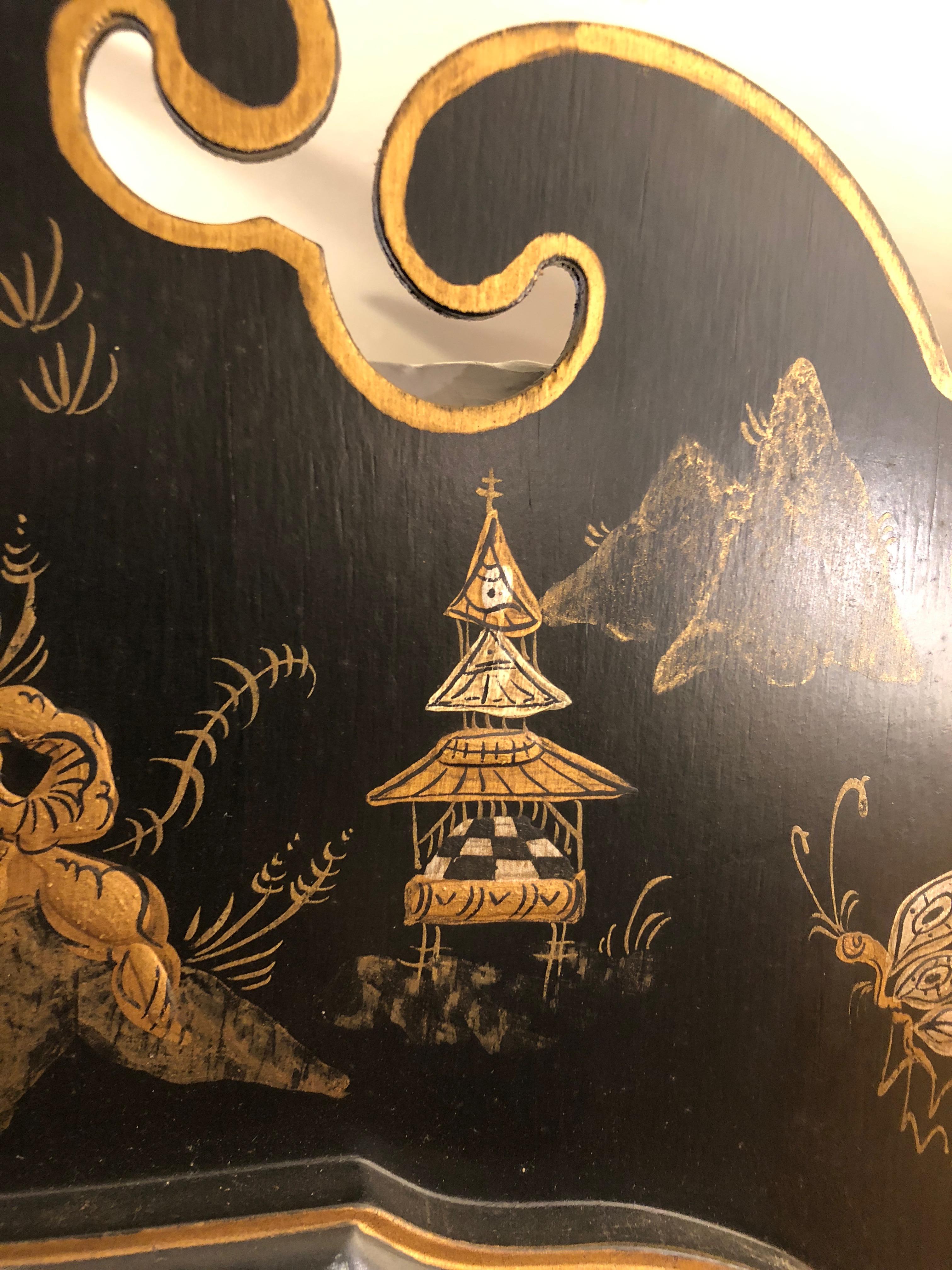 A splendid pair of black and gold hand painted chinoiserie style mirrors having figures, butterflies and pagodas adorning Asian inspired shapely frames with beveled mirrors.