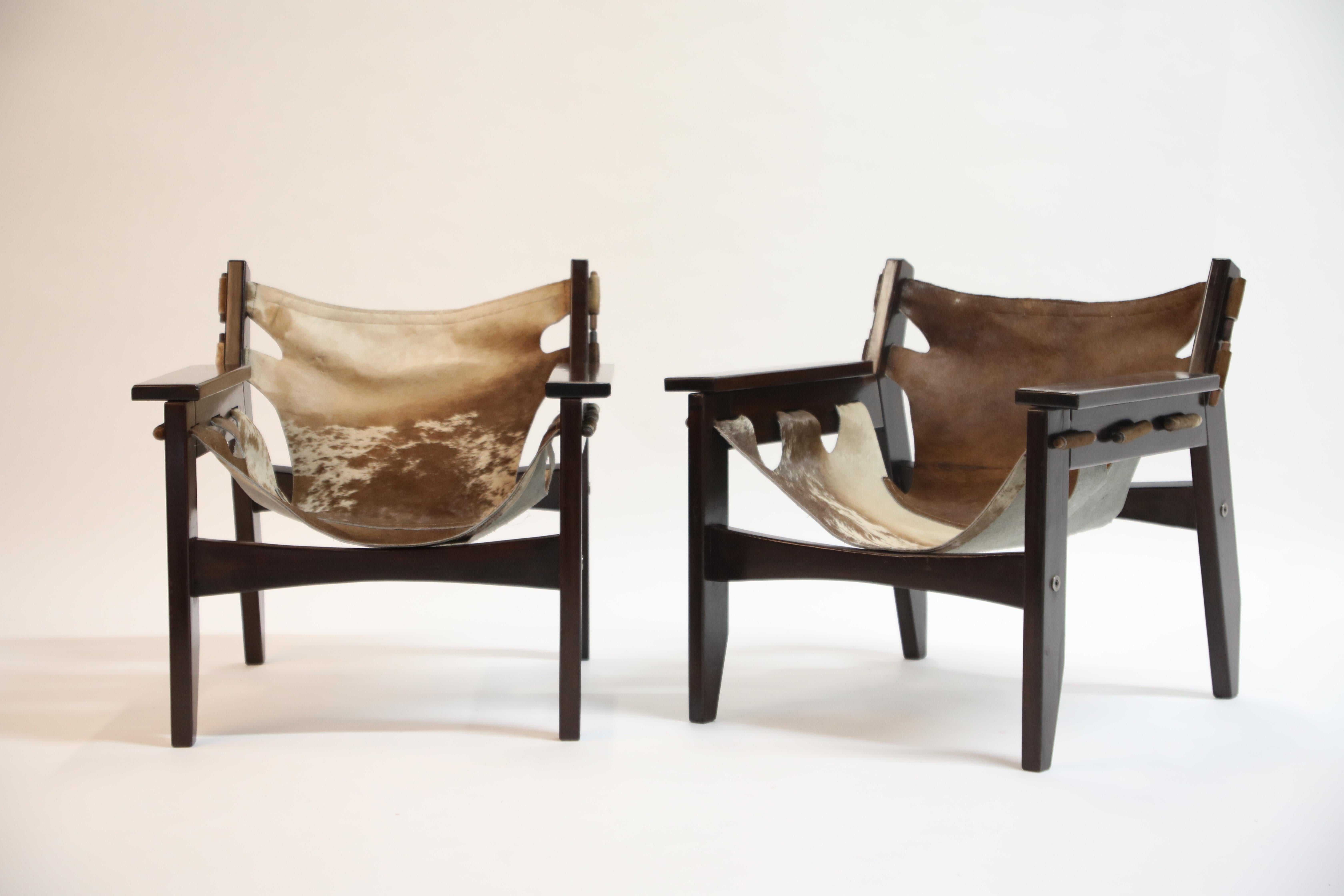 A charming pair and wonderful examples of Kilin chairs by famed Brazilian modern designer Sergio Rodrigues for OCA in 1970s Brazil. Frame is a succulent rosewood and the leather slings are hair-on cowhide. The pattern on each sling is slightly