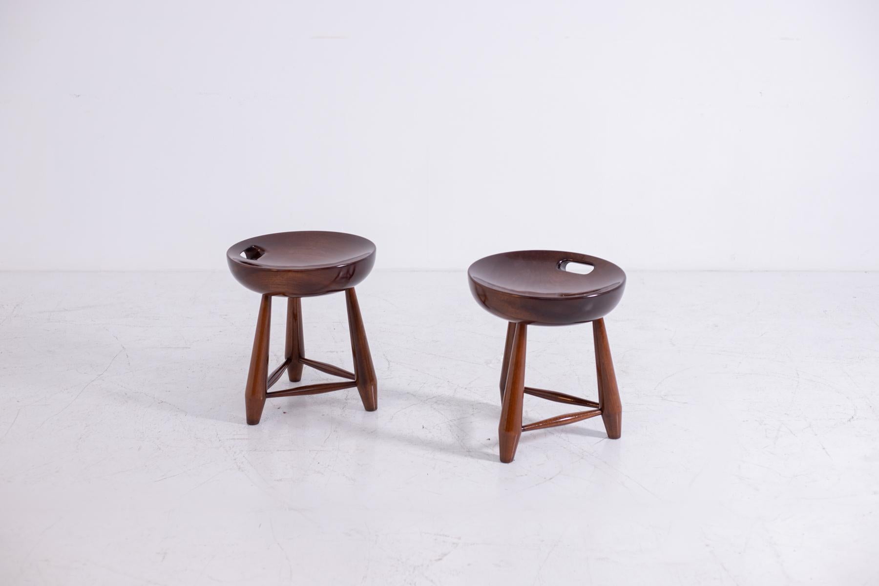 A pair of Sergio Rodrigues' Mocho stools in solid noble wood, circa 1960. Designed in 1954 and produced by the Brazilian company Oca, which Rodrigues founded in 1955. The three-legged Mocho stool is inspired by the traditional cow stools used in