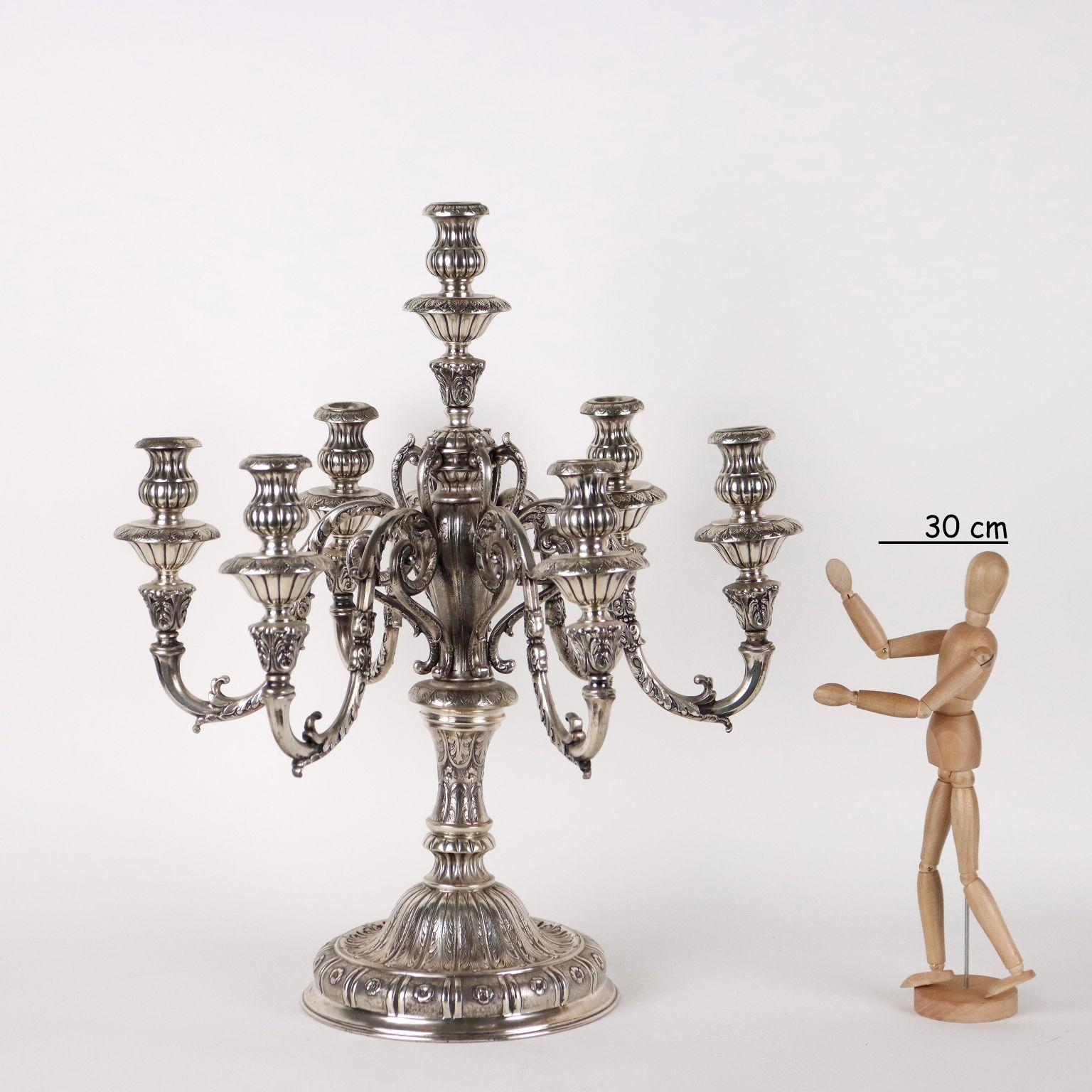 Pair of large seven-flame candelabra in embossed and finely chiselled silver. Rich decorations with plant motifs and arms with leafy volutes. Brand of the silver incusso, the Milanese silversmith's brand is hard to read. 8500 grams.