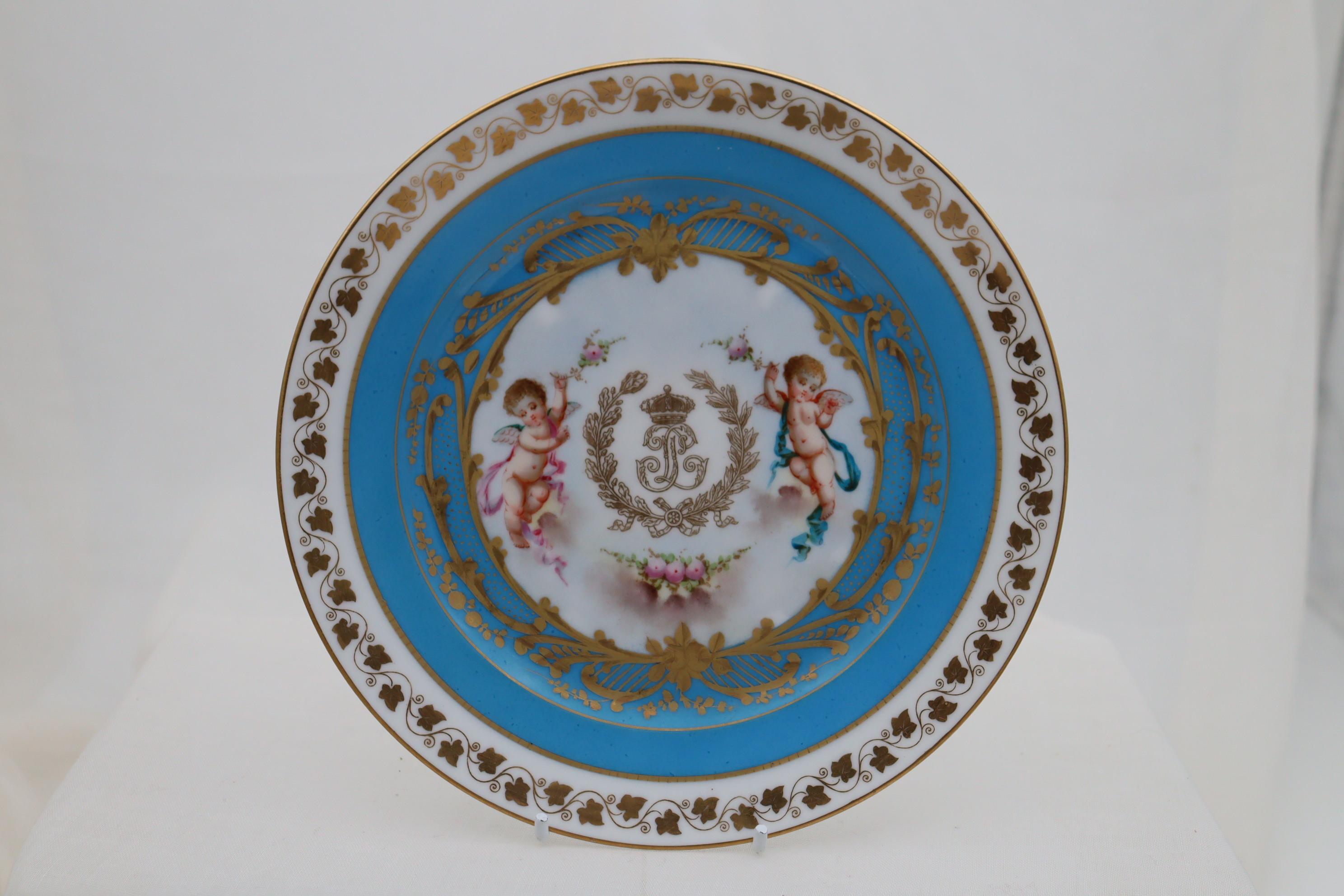 This pair of small Sevres hand painted plates are decorated to the centre with the gilt monogram under a crown, signifying King Louis Phillippe 1 (1773-1850) who reigned as King of France from 1830-1848. Either side of the initials are cherubs