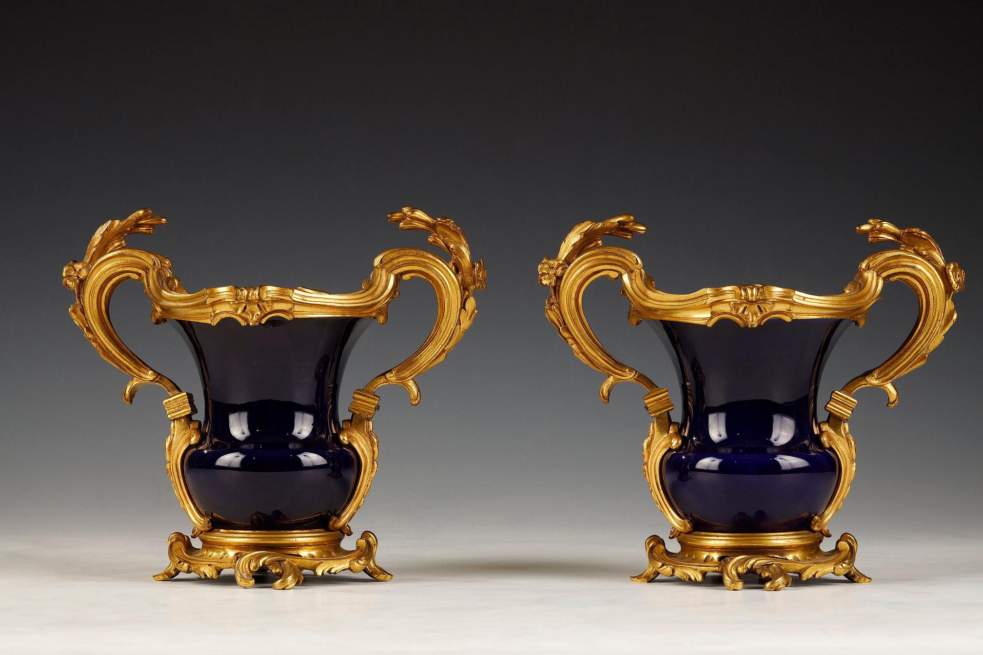 One vase marked SÈVRES and dated (18)68

Pair of small Louis XV-inspired baluster-shaped vases, in gros bleu de Sèvres hard-paste porcelain. Beautiful gilded and chiseled bronze mount decorated with foliage forming the handles and the base.

The