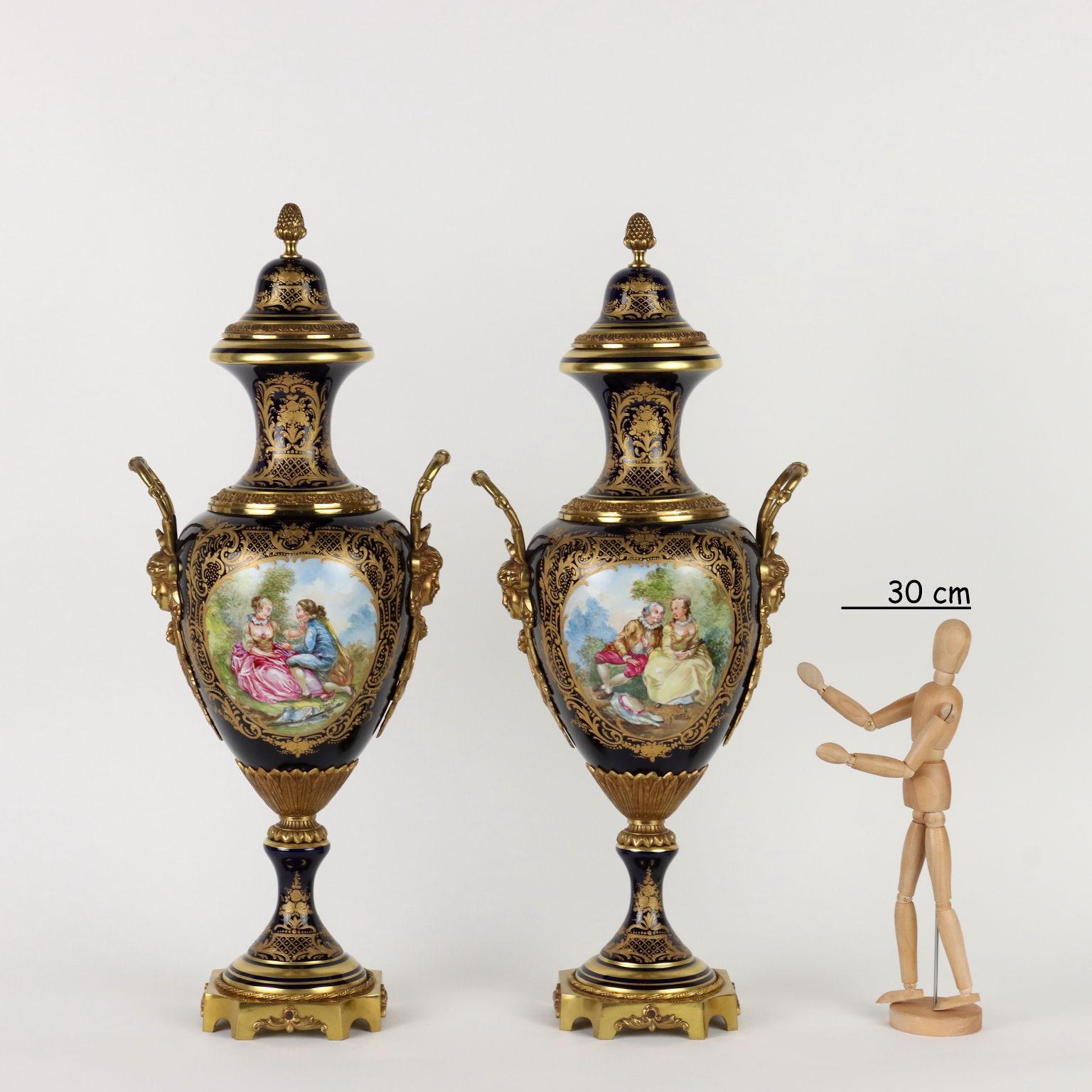 Pair of Sèvres porcelain vases with amorous scenes painted in polychrome inside reserves and signed by Granet. On a cobalt blue background the rich gold decorations with leafy scrolls and plant motifs stand out. The vases are mounted on gilt bronze