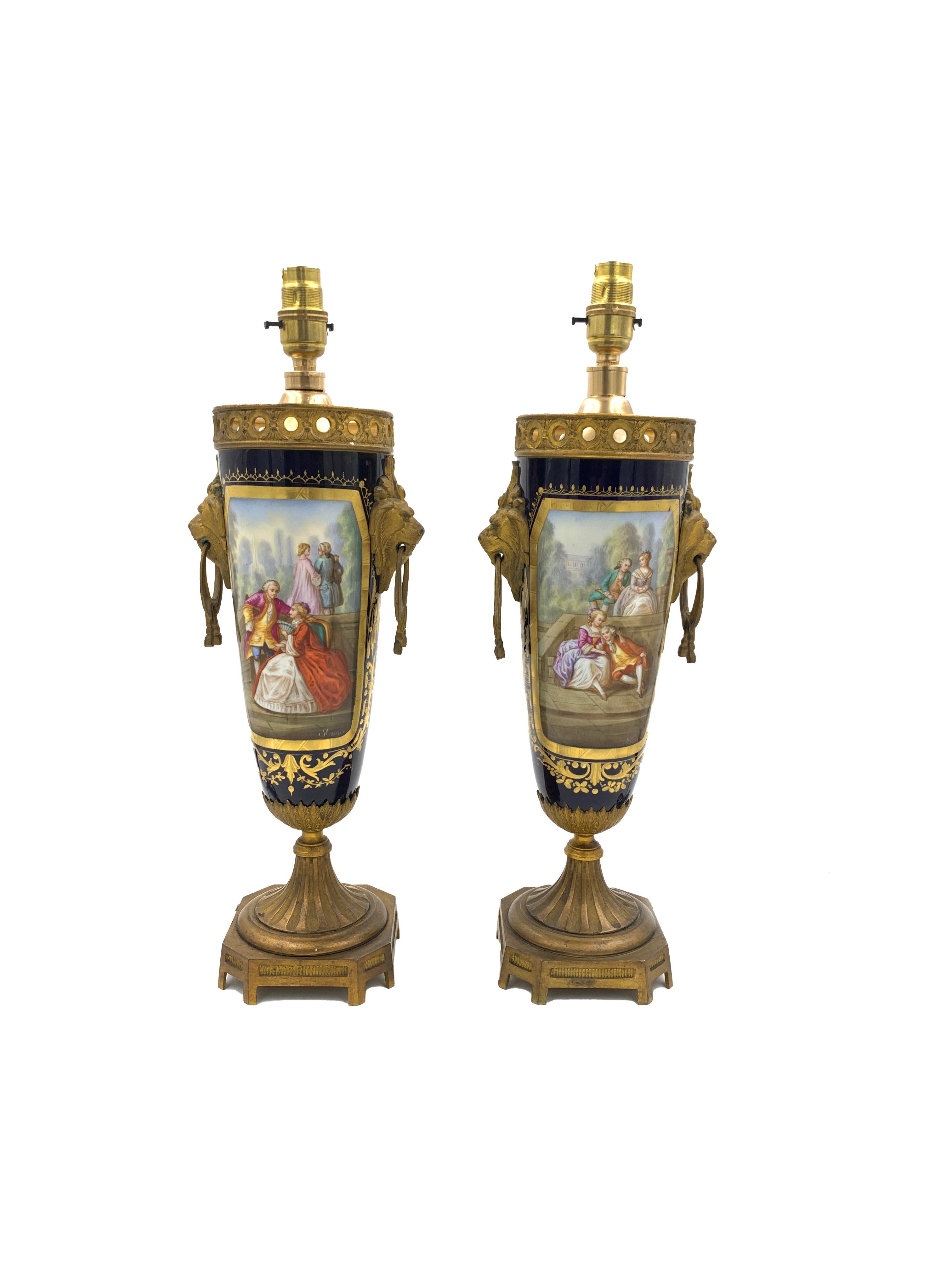 A wonderful pair of French 19th century blue Sèvres style porcelain and ormolu table lamps. Each elegant lamp is raised by a square ormolu base, hand painted in different scenes and signed by the artist.