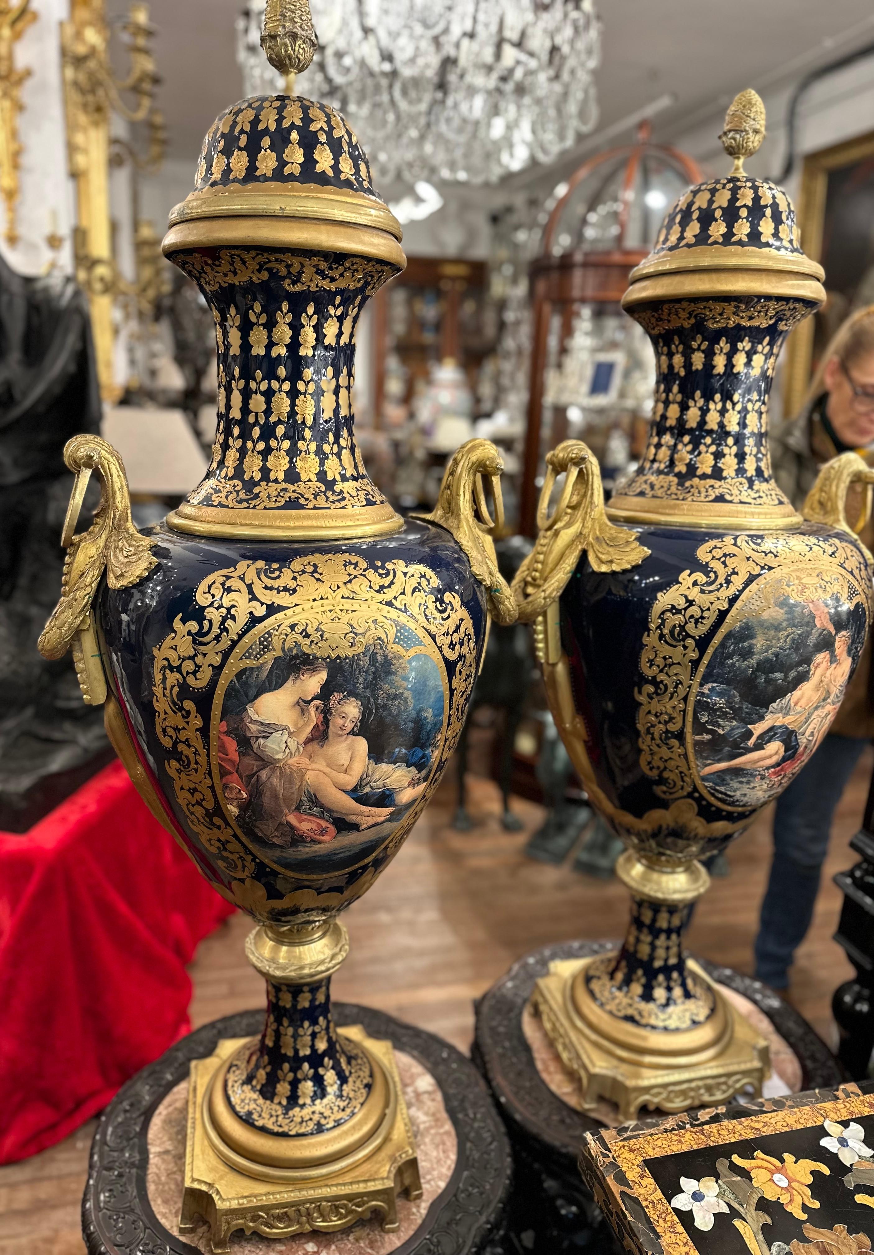 Ein äußerst dekoratives Paar Vasen im Stil von Sèvres in Blau und Gold. Aufwändig und detailreich von Hand gemalt, zeigt es liegende Figuren in einer Landschaft. Idyllisch und klassisch ist das Gemälde der Szene mit frischen Farben und