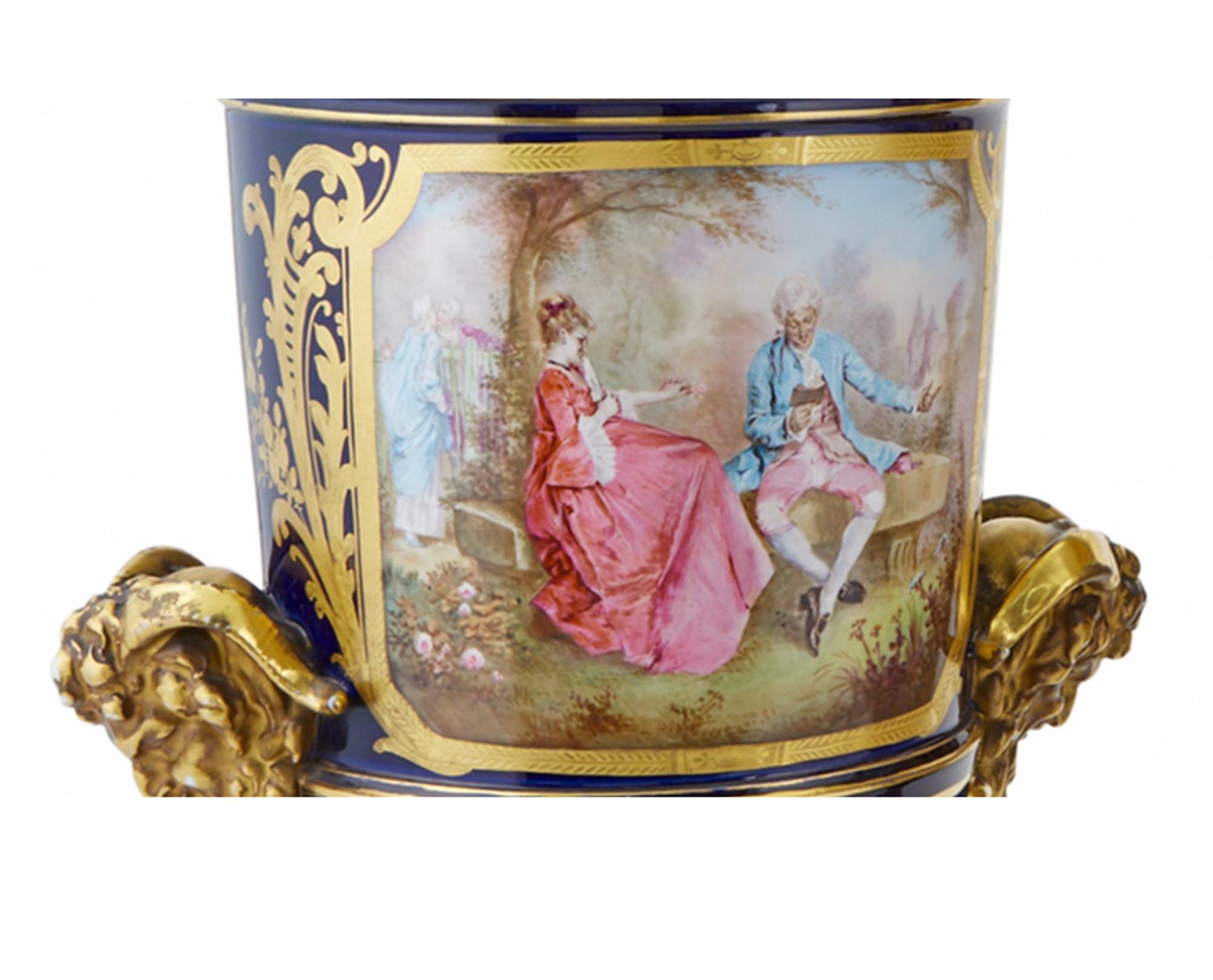 Each of elongated urn form with satyr mask handles and a loose domed cover with a bud finial, decorated on the front side with a reserve painted with an 18th century courtship scene, the back decorated with a reserve depicting a bucolic landscape