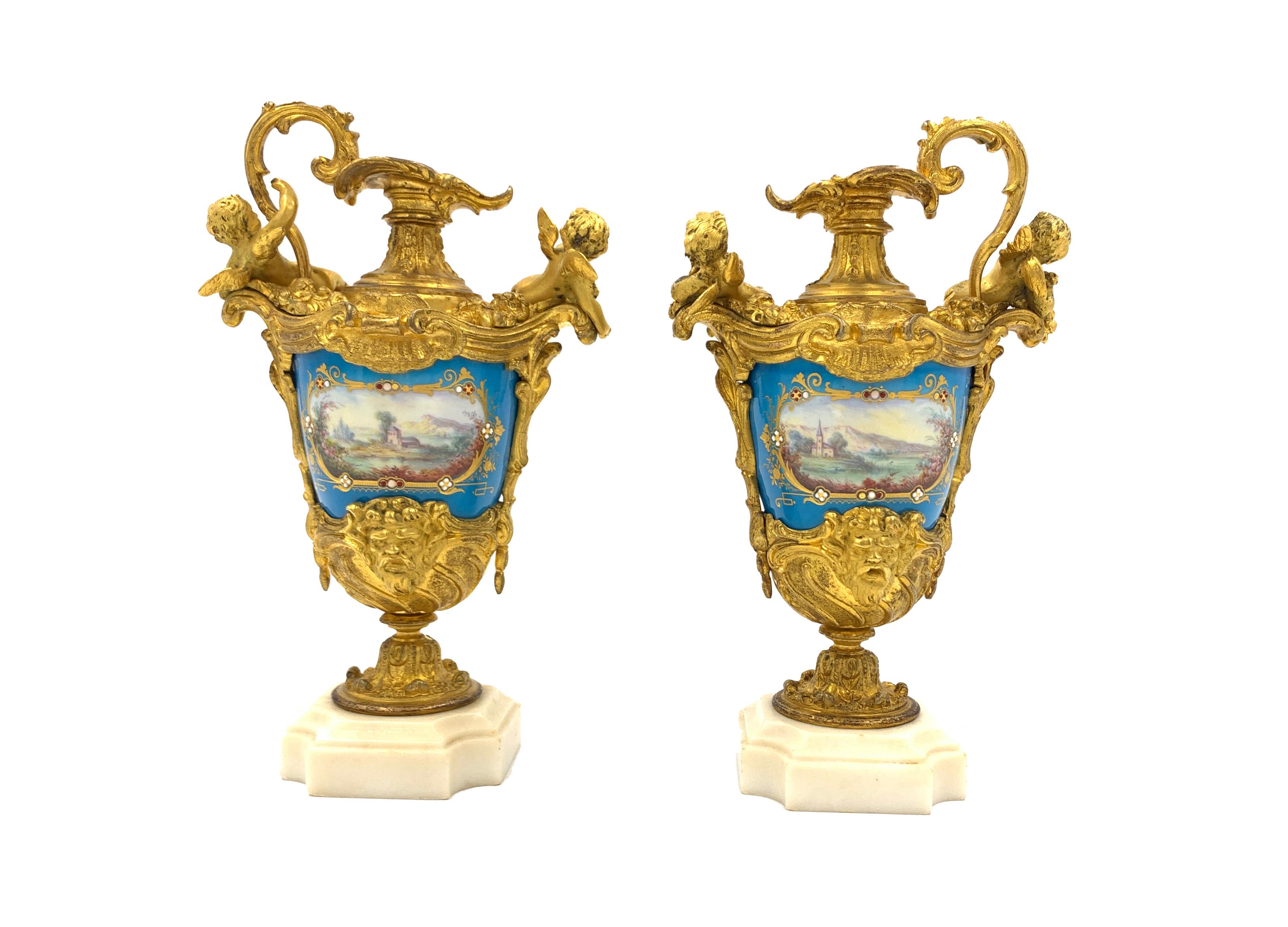 A fine pair of 19th century Sevres style jewelled porcelain and gilt metal ewer vases, decorated with cherubs and romantic continental scenes, on white marble bases.
 