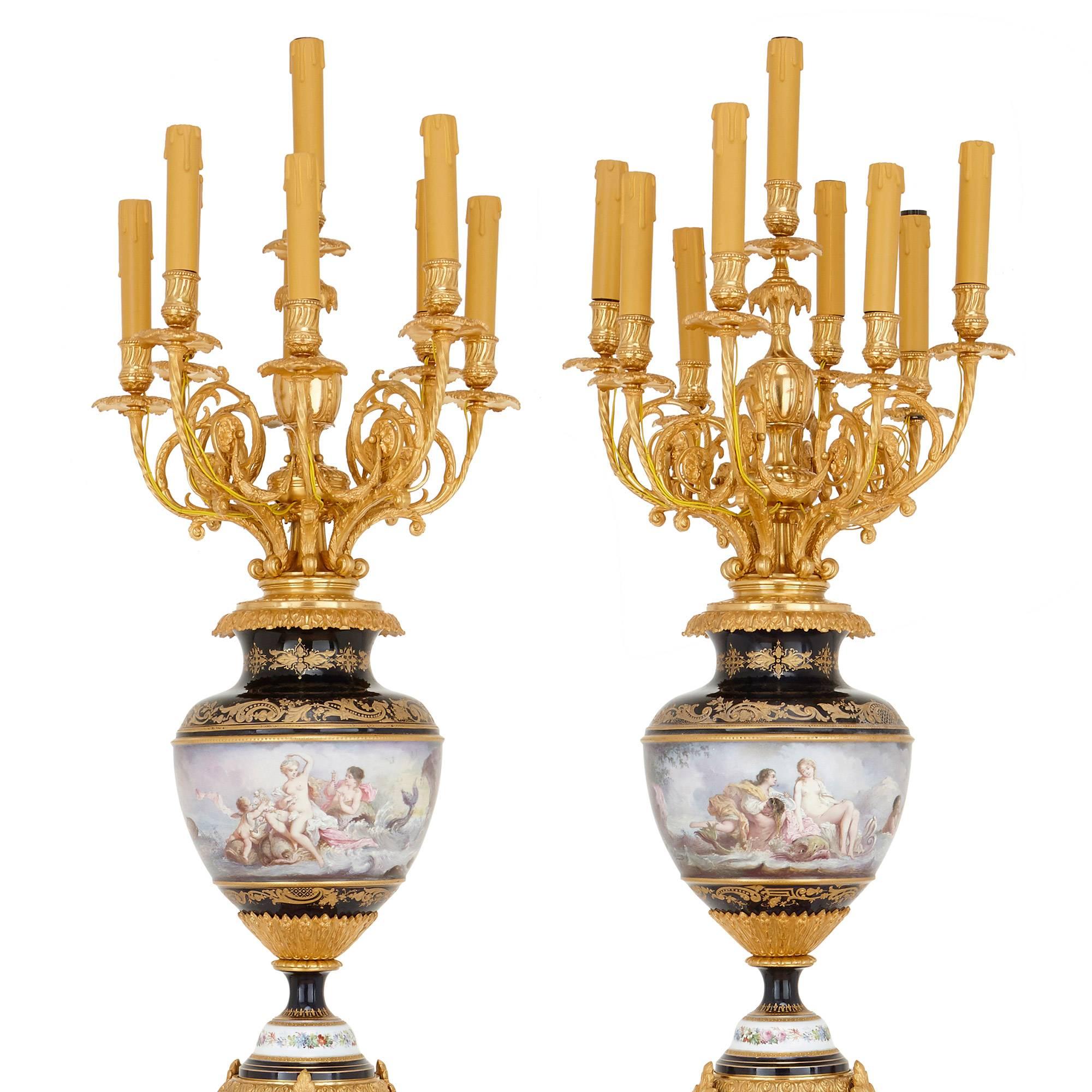 This fine pair of torcheres, or candelabra, are majestic in their size and design, and feature beautifully decorated porcelain bodies. Each torchere takes the form of a gilt bronze candelabrum with nine scrolled, foliate lights with drip pans,