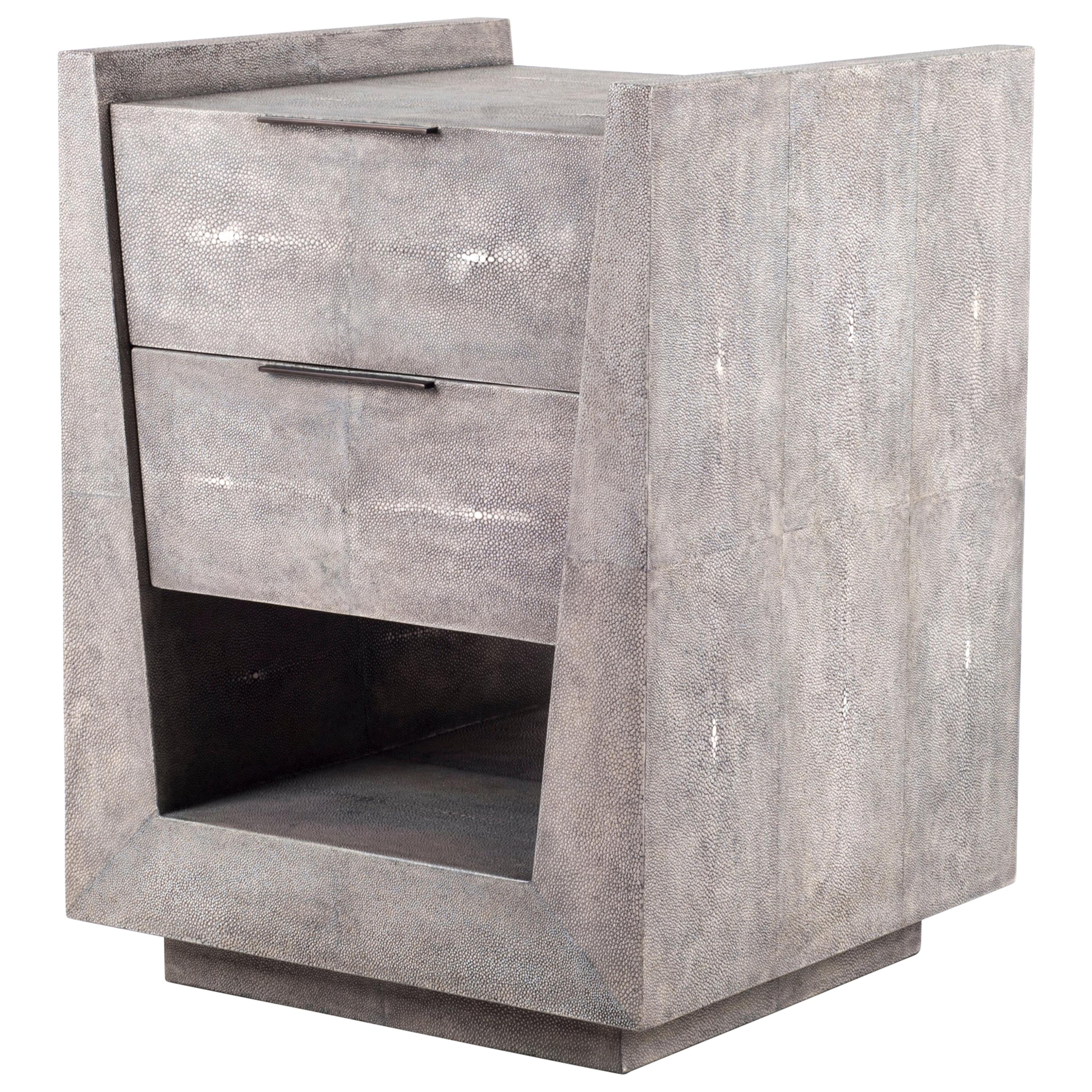 The Lola Bedside by R&Y Augousti is an elegant piece with its subtle geometry. This bedside table is completely inlaid in grey shagreen with discreet bronze-patina brass flat handles for the drawers. The drawers are inlaid in gemelina wood. This