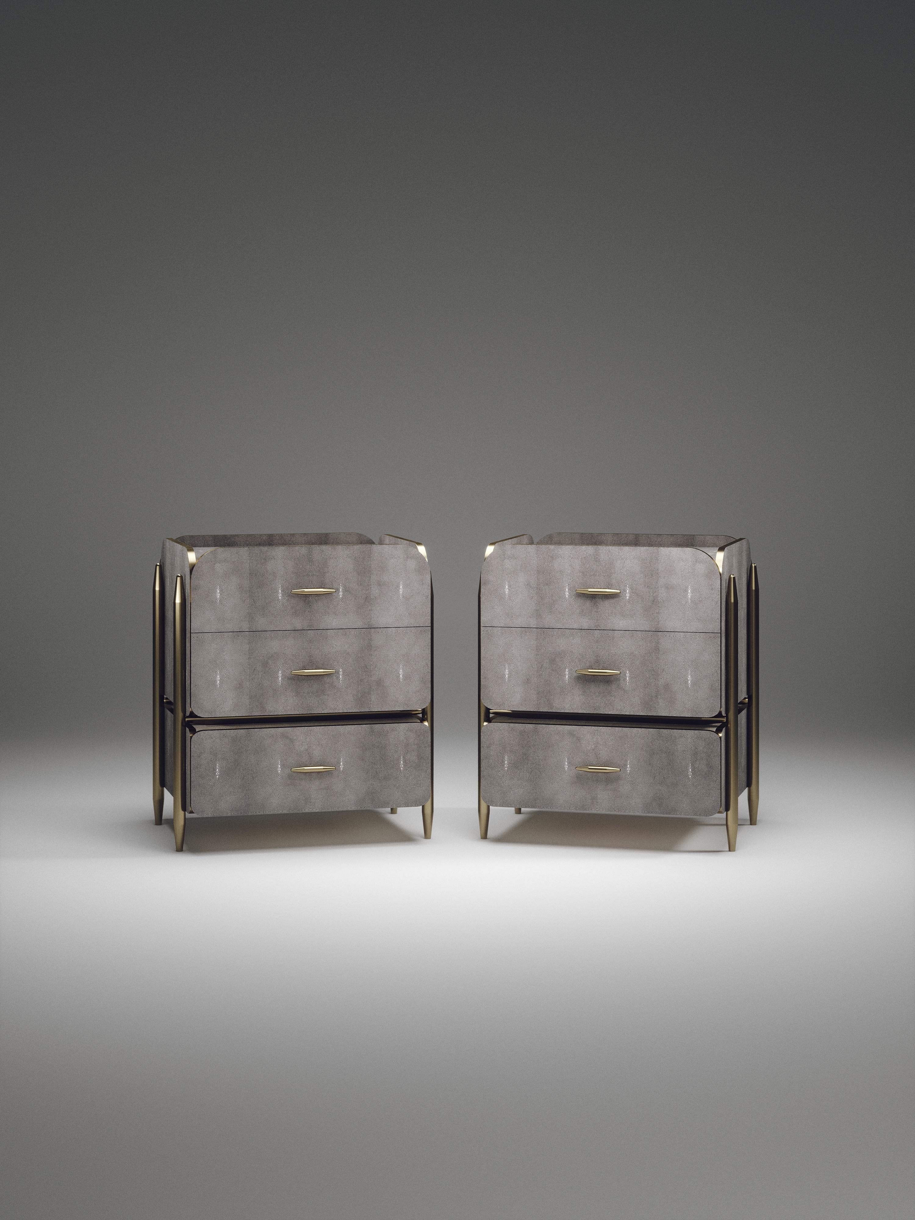 The Pair of Dandy Square Bedside Tables by Kifu Paris are elegant and luxurious home accents, inlaid in light grey shagreen with bronze-patina brass details. This piece includes 3 drawers total and the interiors are inlaid in gemelina wood veneer.