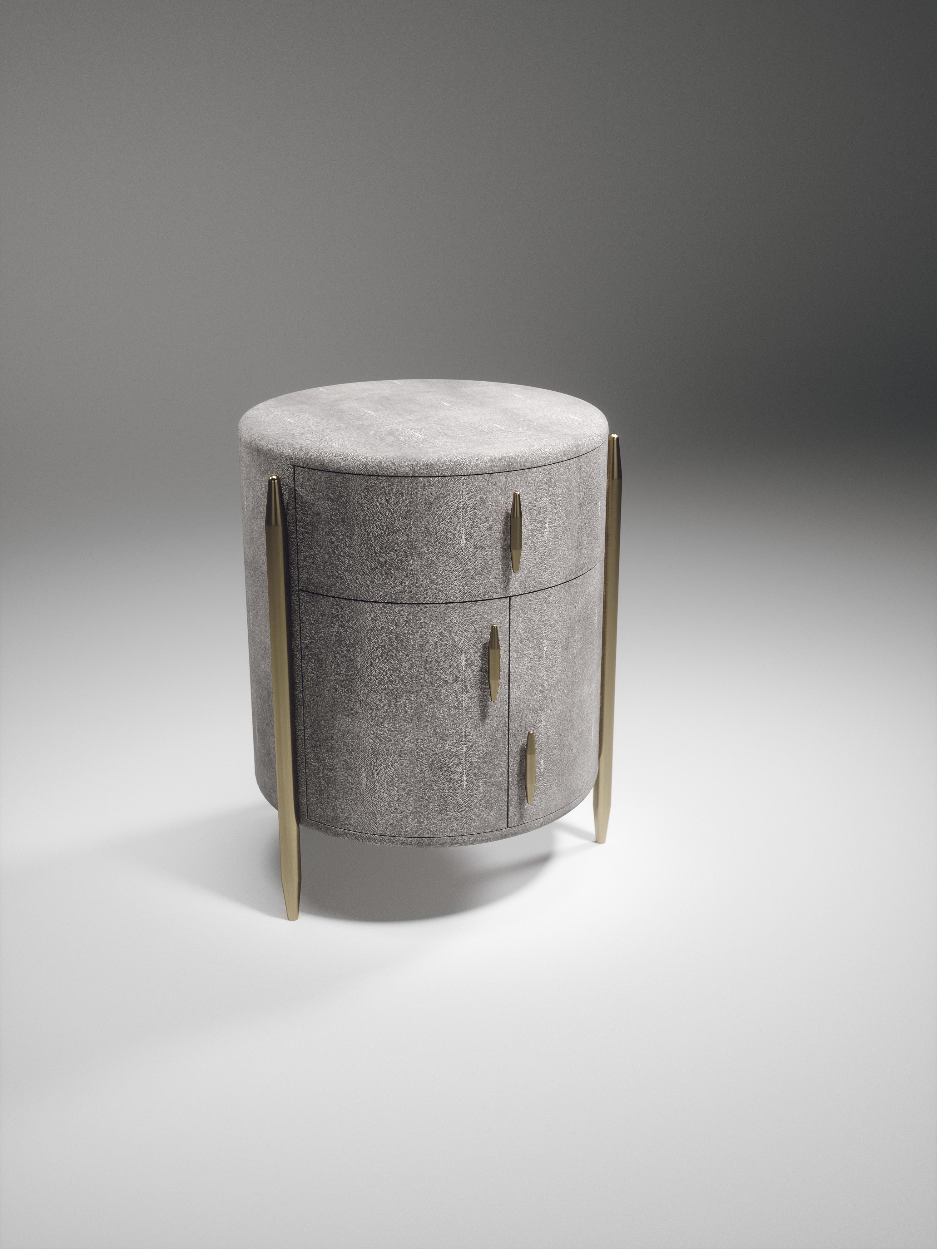 The pair of dandy round bedside tables by Kifu Paris are elegant and luxurious home accents, inlaid in light grey shagreen with bronze-patina brass details. This piece includes 1 drawer total and a cabinet below; the interiors are inlaid in gemelina