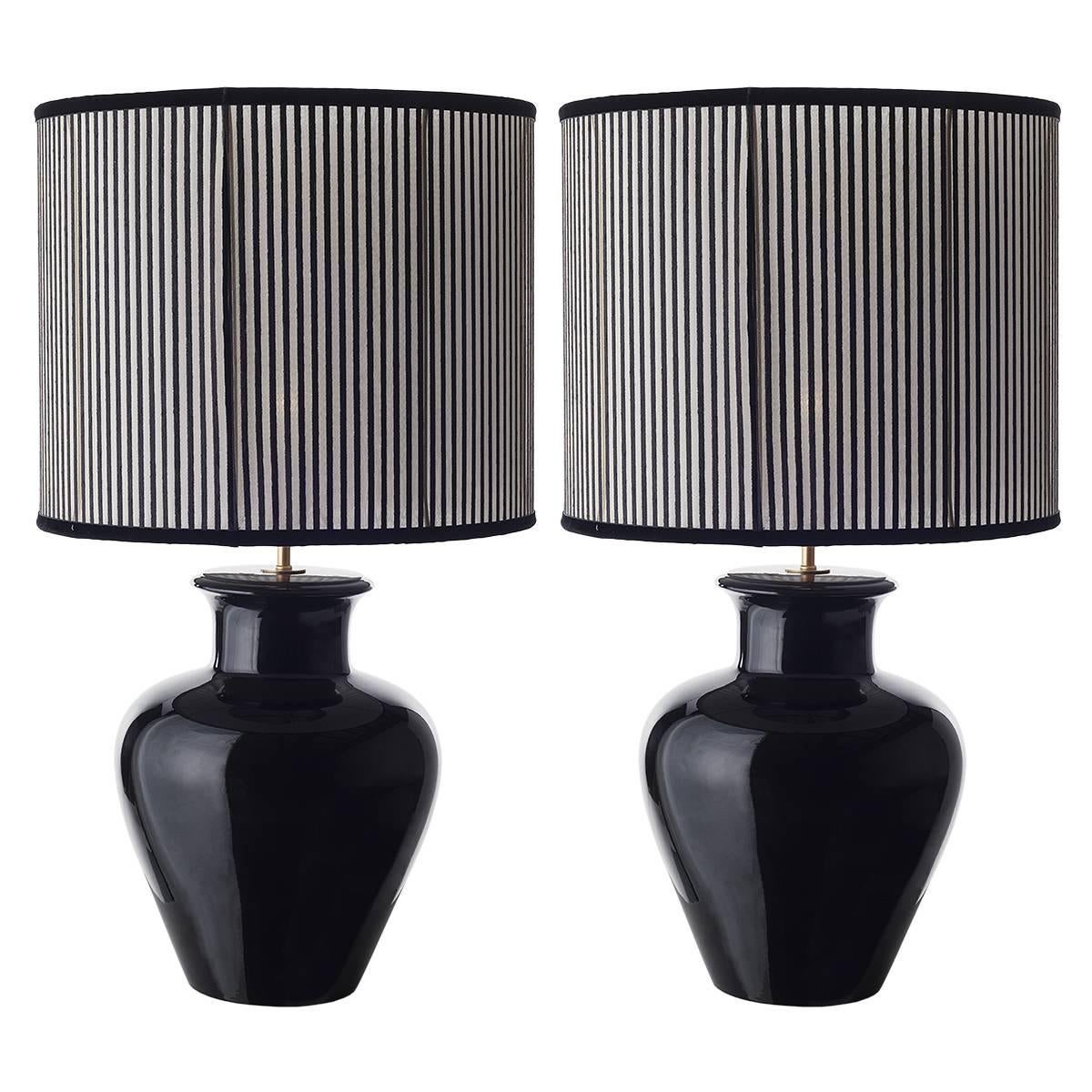 Pair of shapely ceramic table lamps and shades.
The perfect attractively shaped body of this table lamp is emphasized by the glossy black glaze and the seductive but geometric, fancy fabric the shade is made of.
Wired to your request, one E27/E26