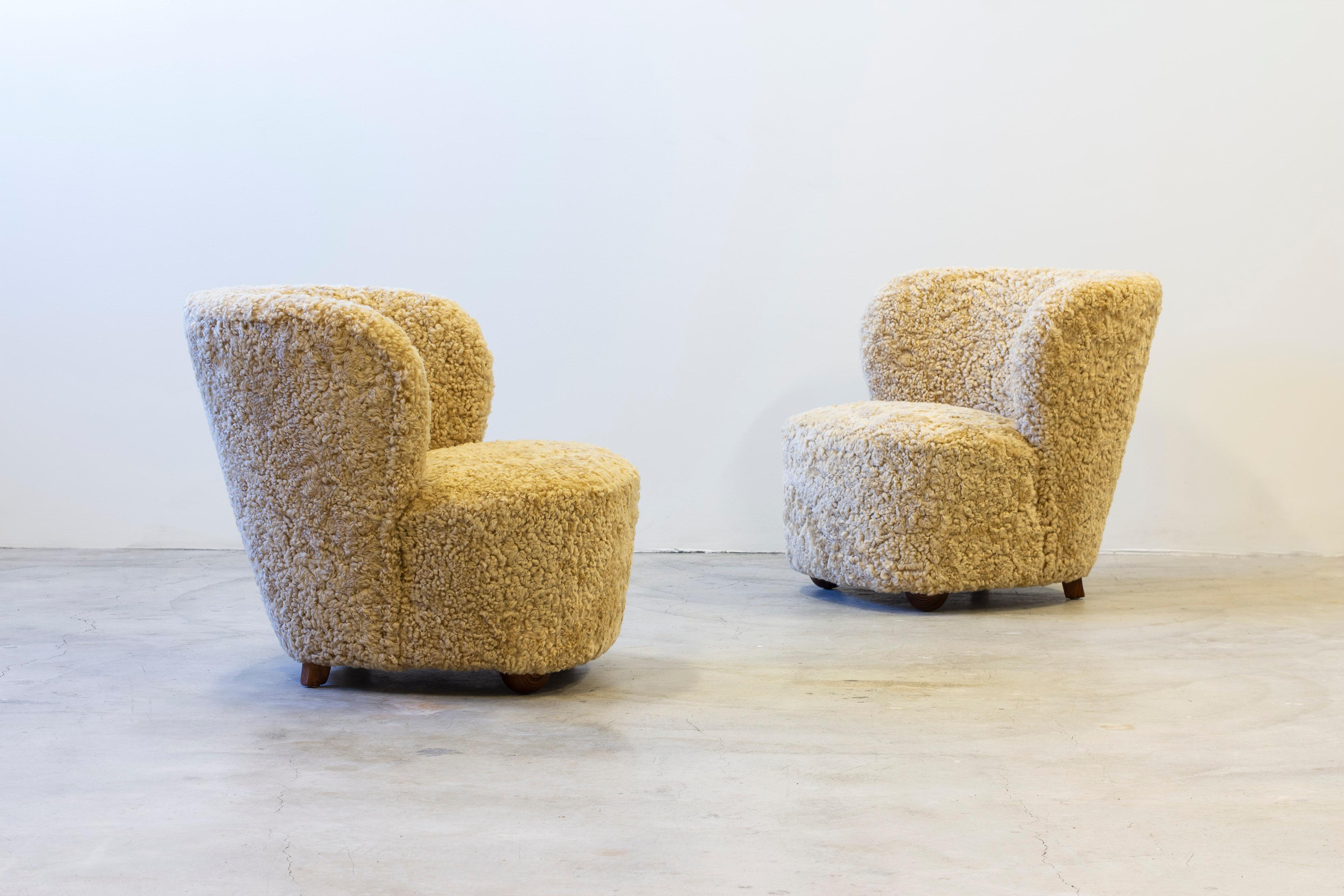 Pair of lounge chairs in the manner of Viggo Boesen. Designed and produced in Denmark by Danish cabinetmaker. Legs in dark stained oak and Beige colored sheepskin upholstery. Upholstery is new and in excellent condition. Very good condition with few