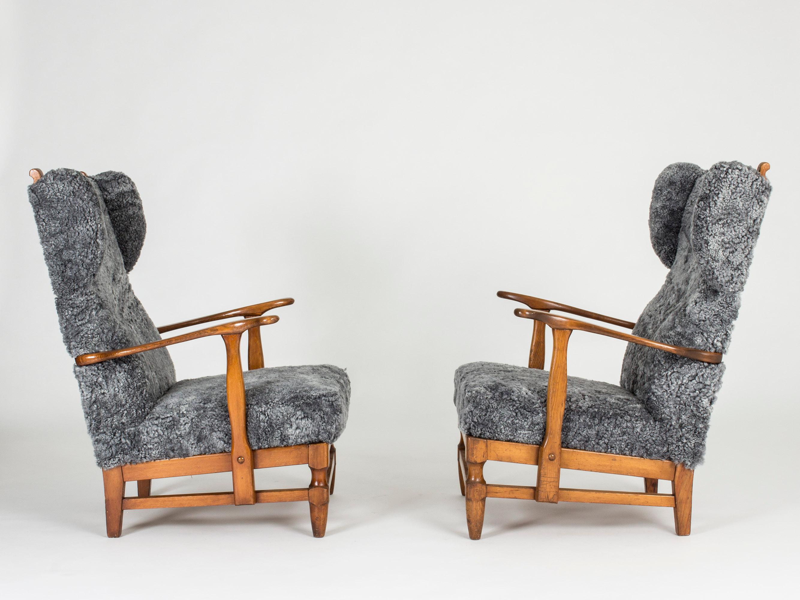 Pair of stout and elegant lounge chairs by Gunnar Göperts. Stained pine frame with beautiful, rustic details and grey sheepskin upholstery.