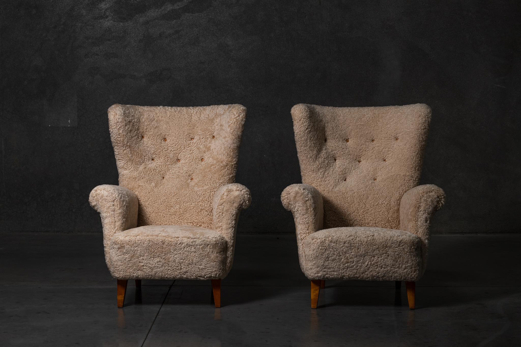 Pair of Scandinavian wingback sheepskin easy chairs with leather buttons. Made in Sweden circa 1940s.