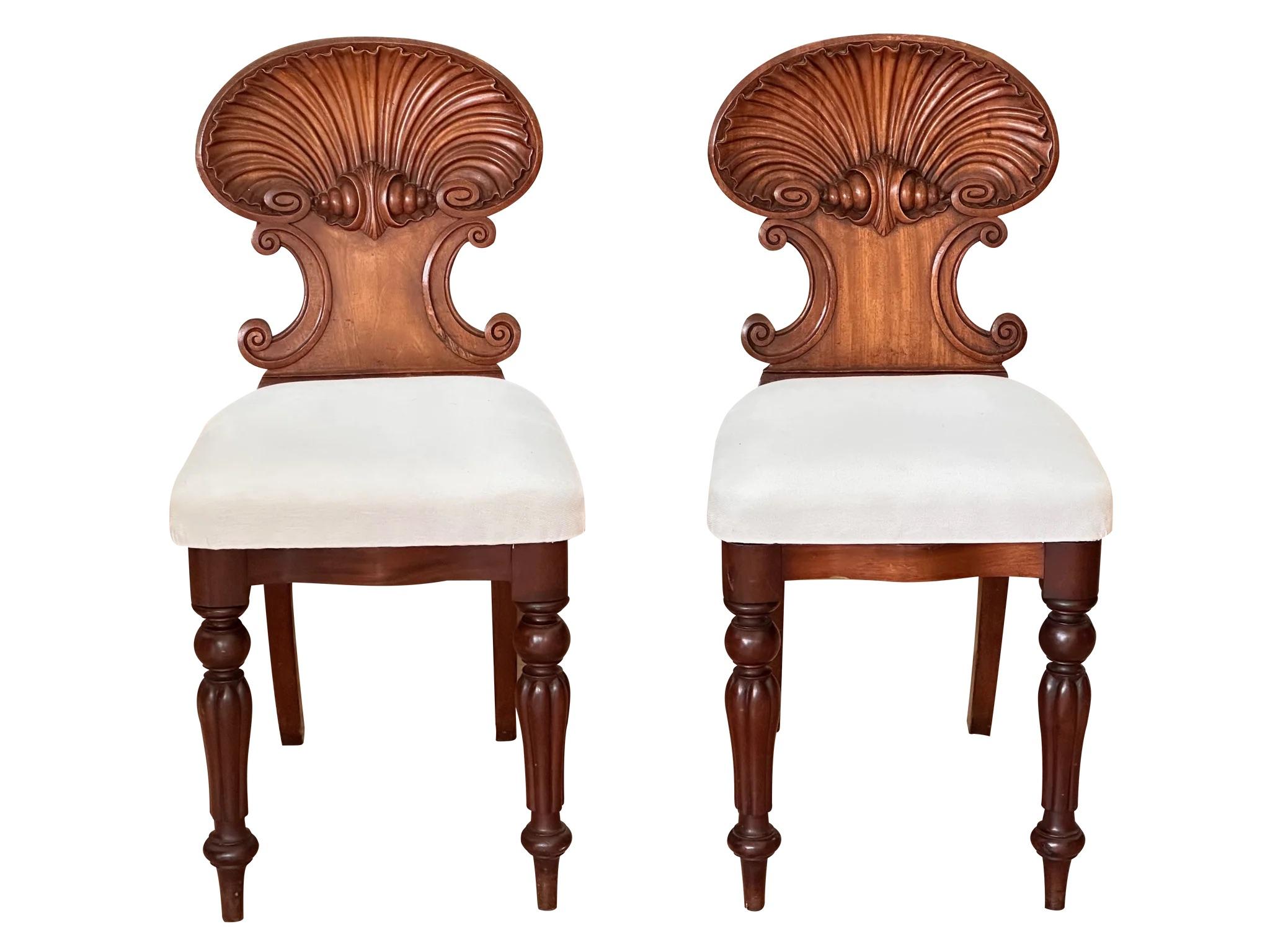 A pair of especially finely carved shell-back hall chairs, late 18th-early 19th Century, likely Irish, Mahogany with later upholstered seats.  SH 19”.
