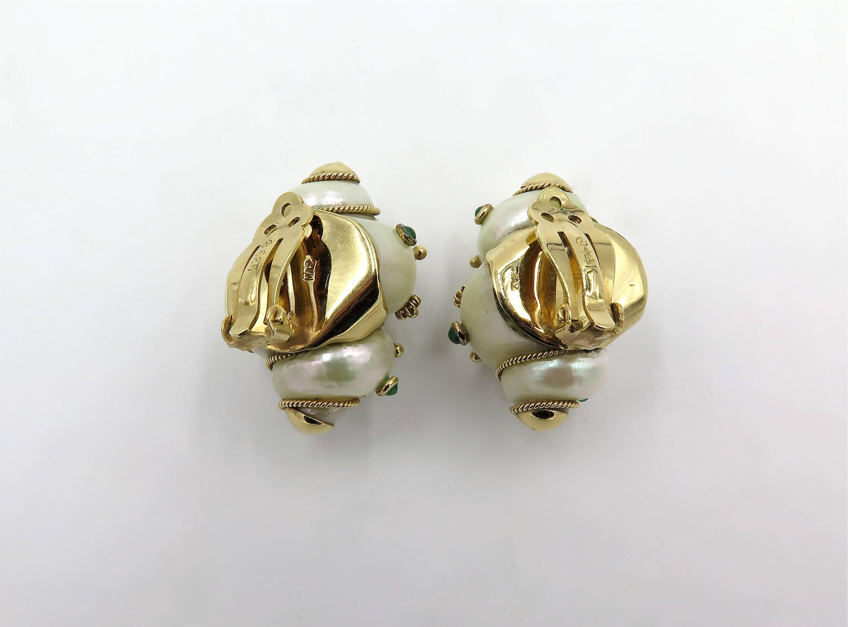 A pair of 14 karat yellow gold, shell and emerald earrings. Maz. Circa 1970. Each set with a white turbo shell, studded with cabochon emeralds and fluted gold beads, enhanced by gold rope work. Length is approximately 1 1/4 inches. Gross weight is