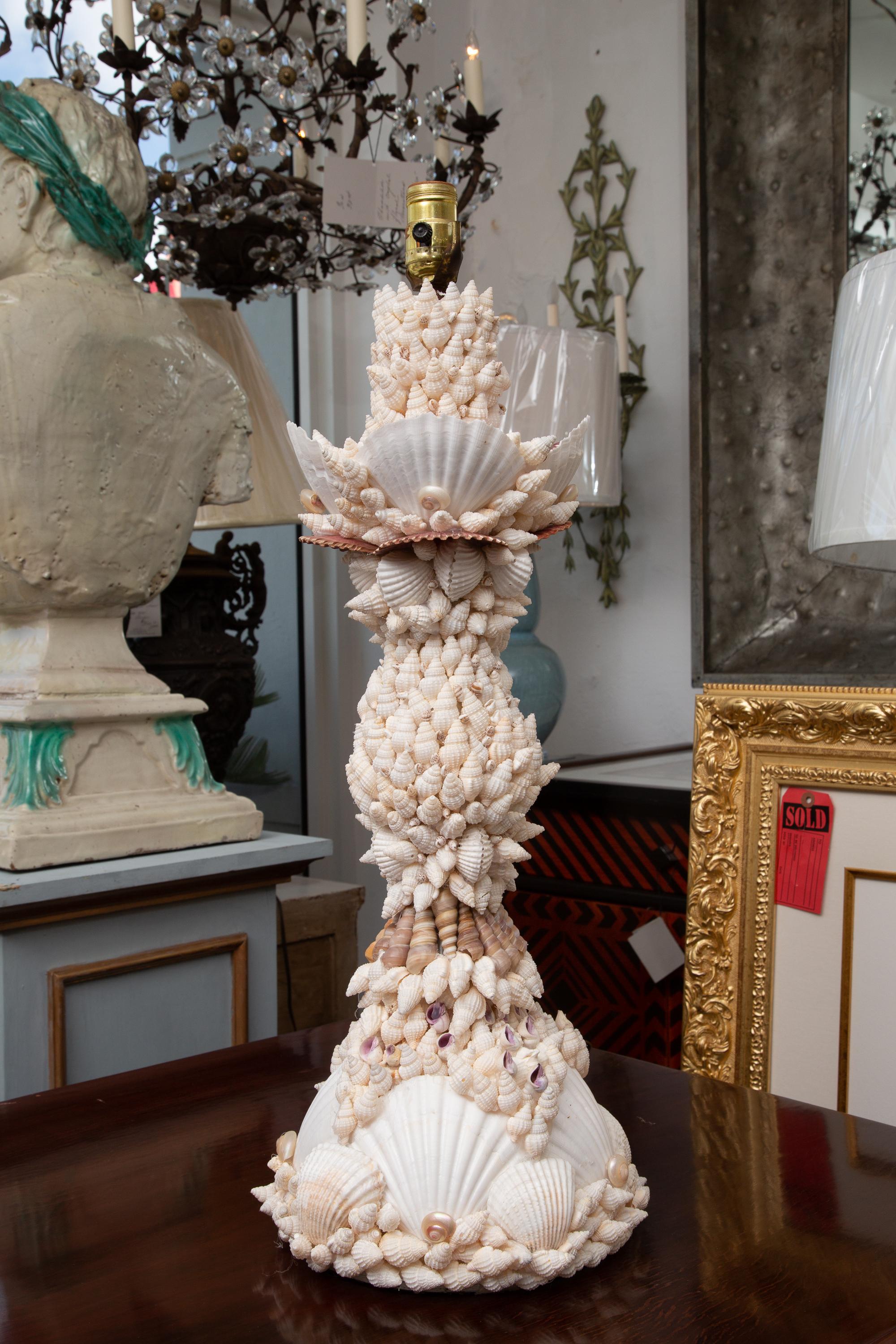 This is a pair of custom table lamps, encrusted overall with a variety of shells. 20th century.