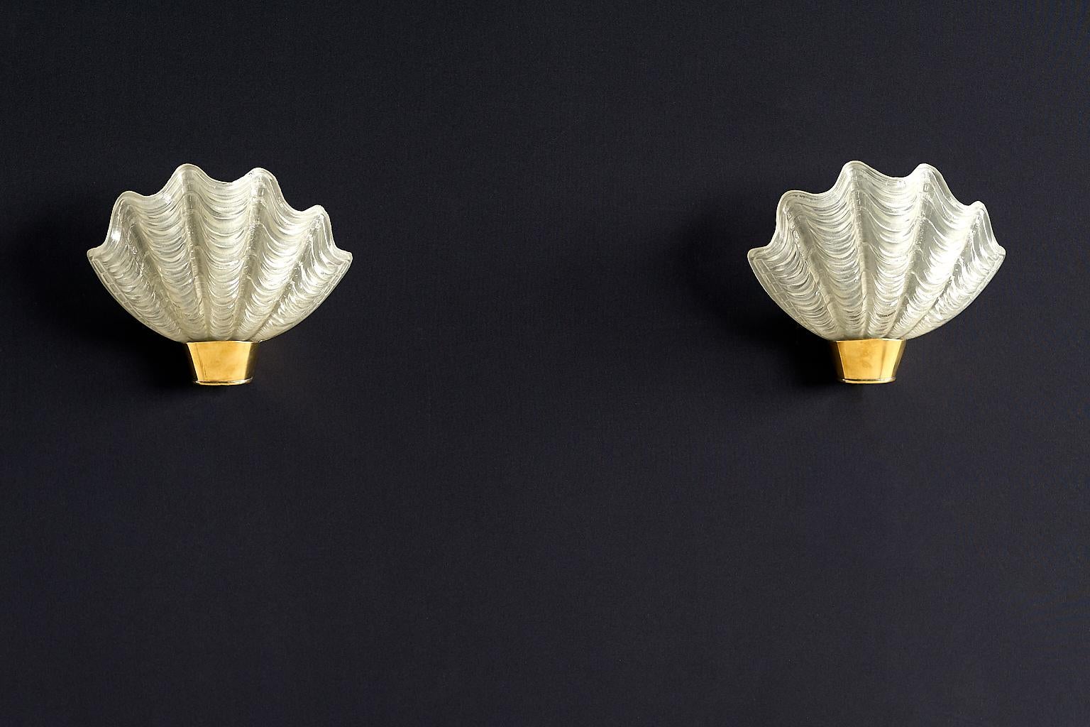 This elegant pair of wall lamps was manufactured by the Swedish company ASEA Skandia in the 1940s. The shell shaped glass shades rest on a brass fitting. The corrugated surface of the glass offers a pleasantly diffused light. Marked with ASEA