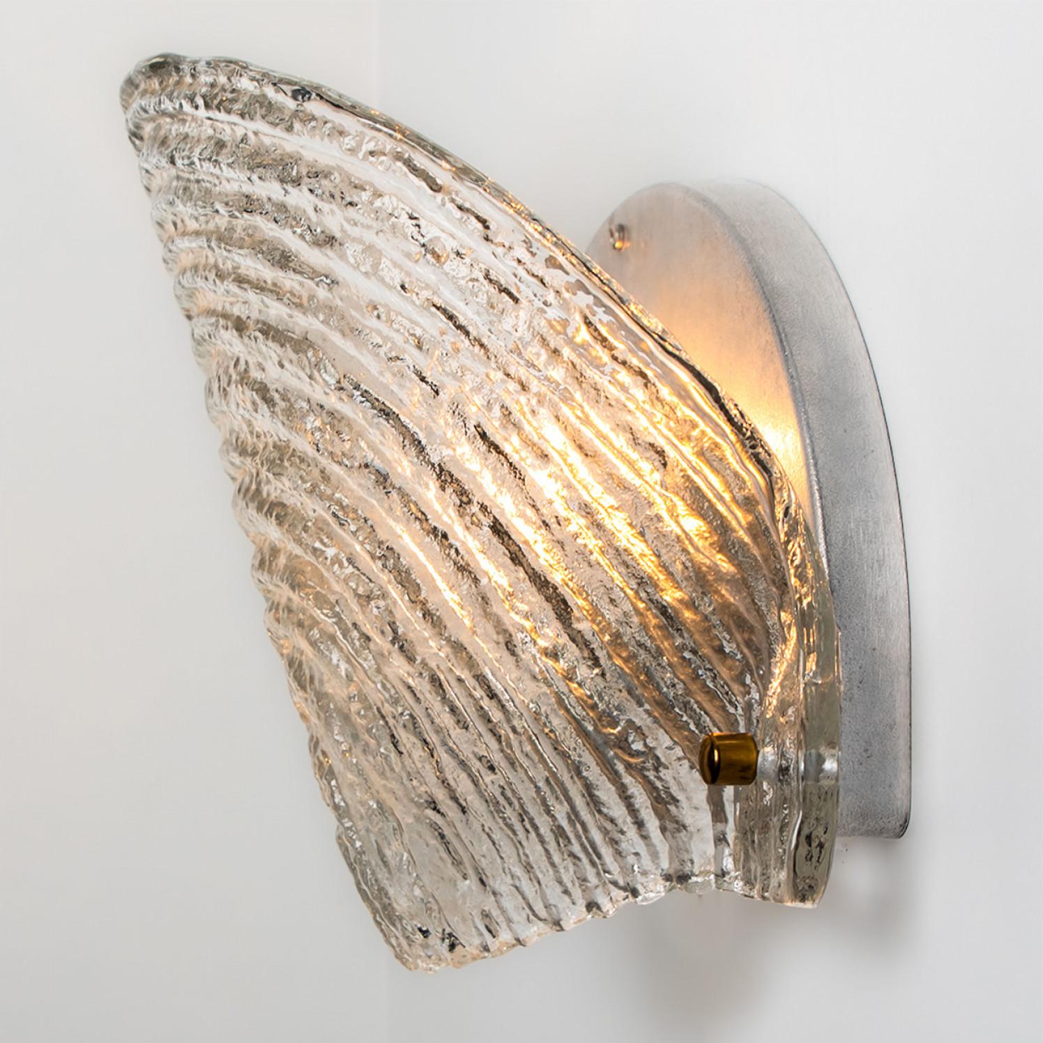 Pair of Shell shaped wall lights in ribble textured glass with silver details. Manufactured by Glashütte Limburg in Germany during the 1970s. (early 1970s).

Nice craftsmanship. Minimal, geometric and simply shaped design.

Dimensions:
Height: 9.84