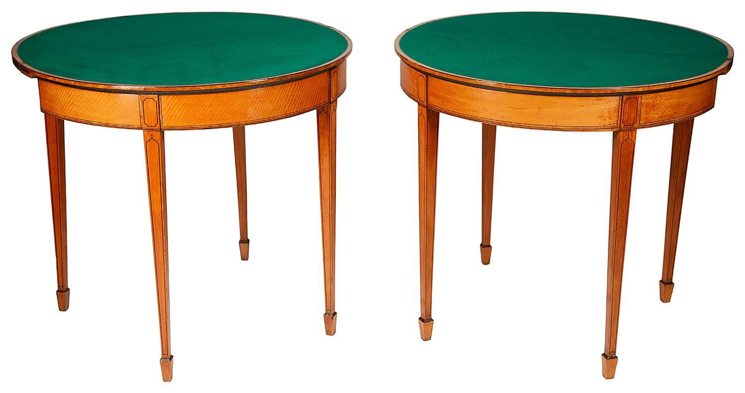 A good quality pair of 18th century Sheraton period Satinwood card tables, each with crossband tops, opening to reveal card play surfaces. The frieze also veneered in Satinwood with crossbanding, ebony string inlaid panels to the tops and to the