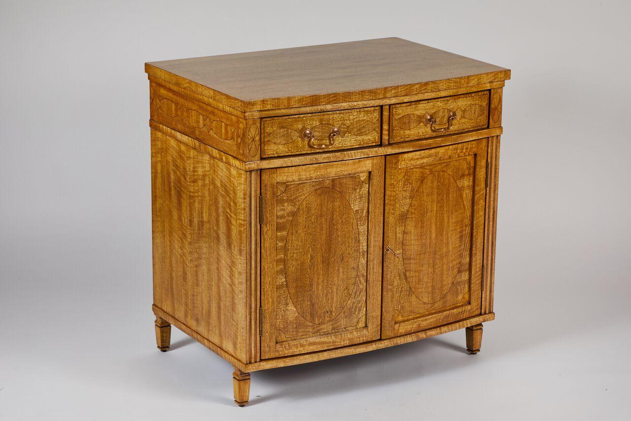 Pair of custom Satinwood cabinets in the Sheraton Revival style. This beautifully proportioned pair of slightly bow-fronted cabinets feature wonderful satinwood veneers, inlaid banding, and oval inlaid decoration at doors. They each have two useful