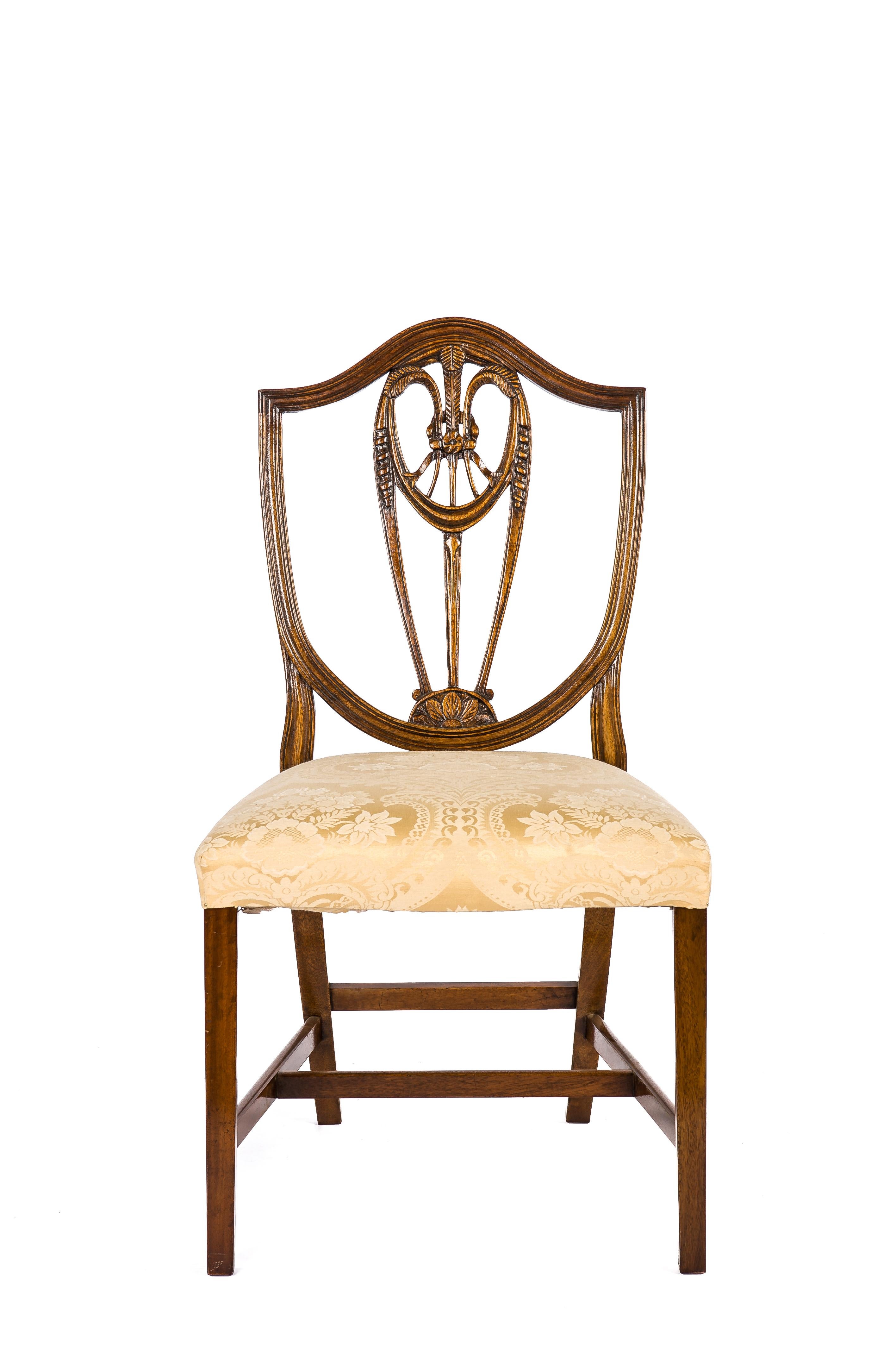 Beautiful pair of George III hand-carved mahogany dining chairs in the manner of George Hepplewhite.
Both chairs have a shield-shaped lyre back with wheat ear decoration, square tapering legs, and cross stretchers. The solid hand-carved mahogany