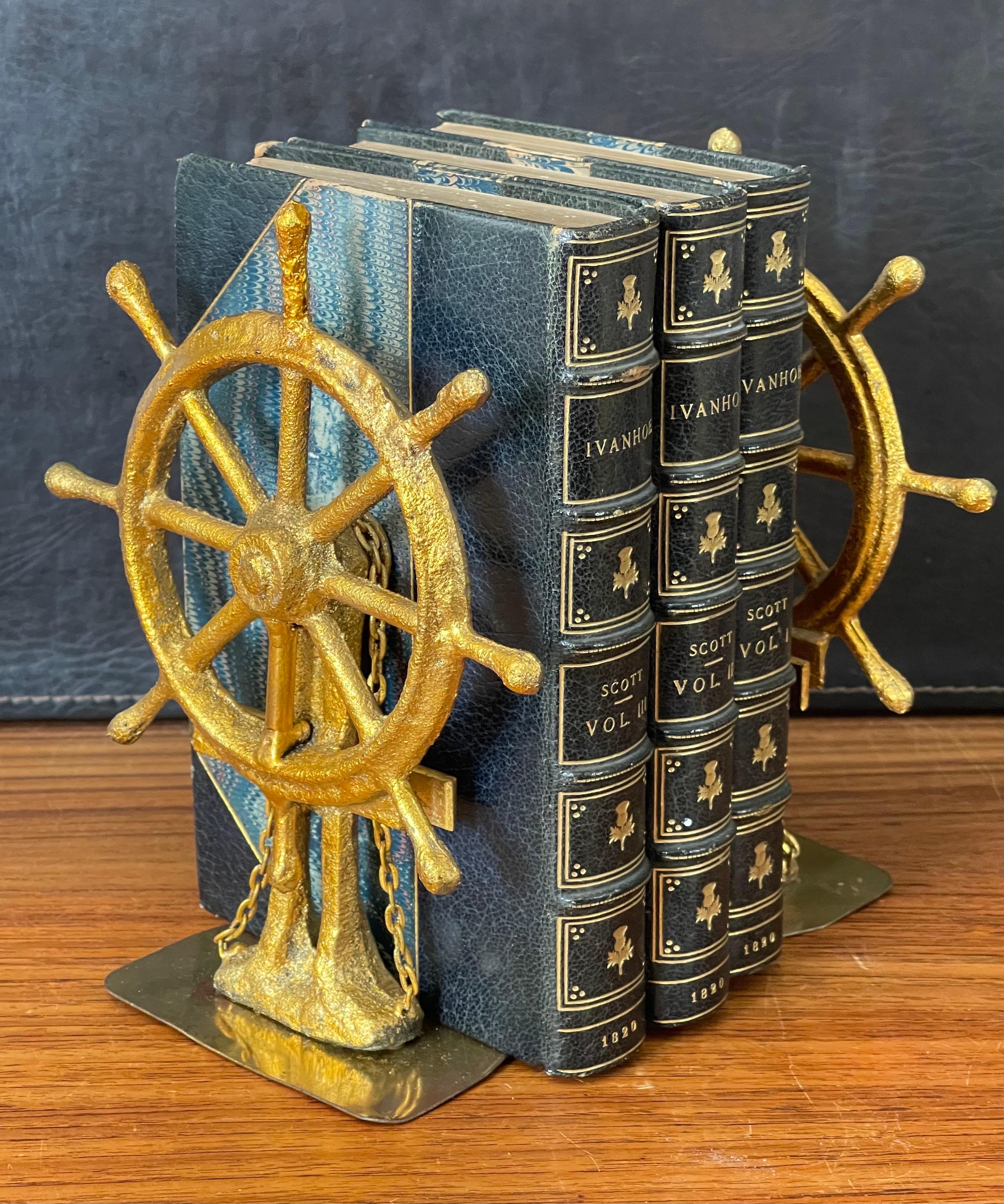 Excellent and rare pair of ship wheel bookends in gold leaf finish by Curtis Jere for Artisan House, circa 1977. The pair are signed and dated and are in very good vintage condition with a wonderful patina. They measure 12
