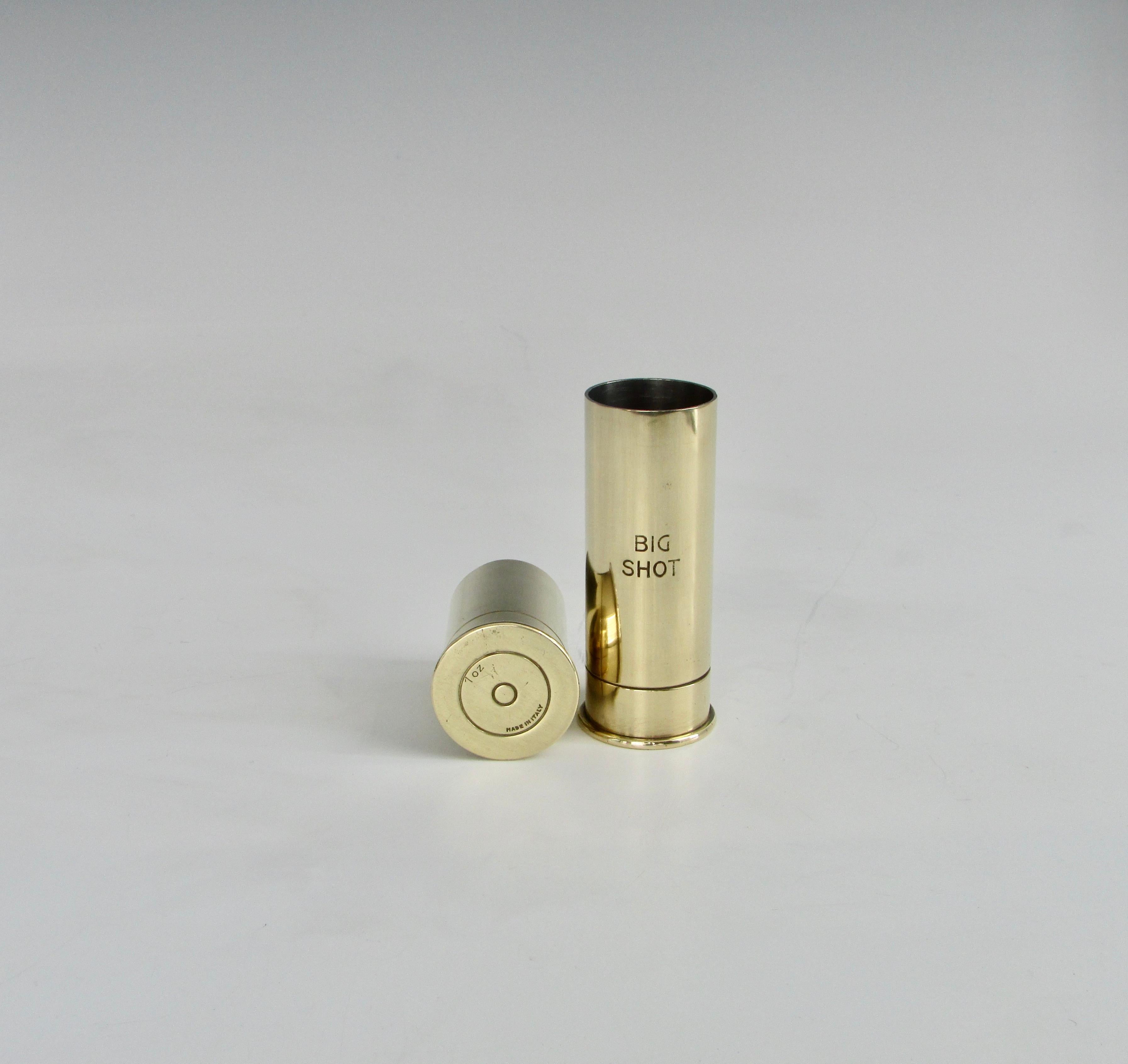 Big shot little shot pair of polished brass shot glasses marked one ounce and two ounce. Styled to look like shotgun shells. Polished brass with tinned or silvered interiors. Measure: 2.25 and 3.5 tall.