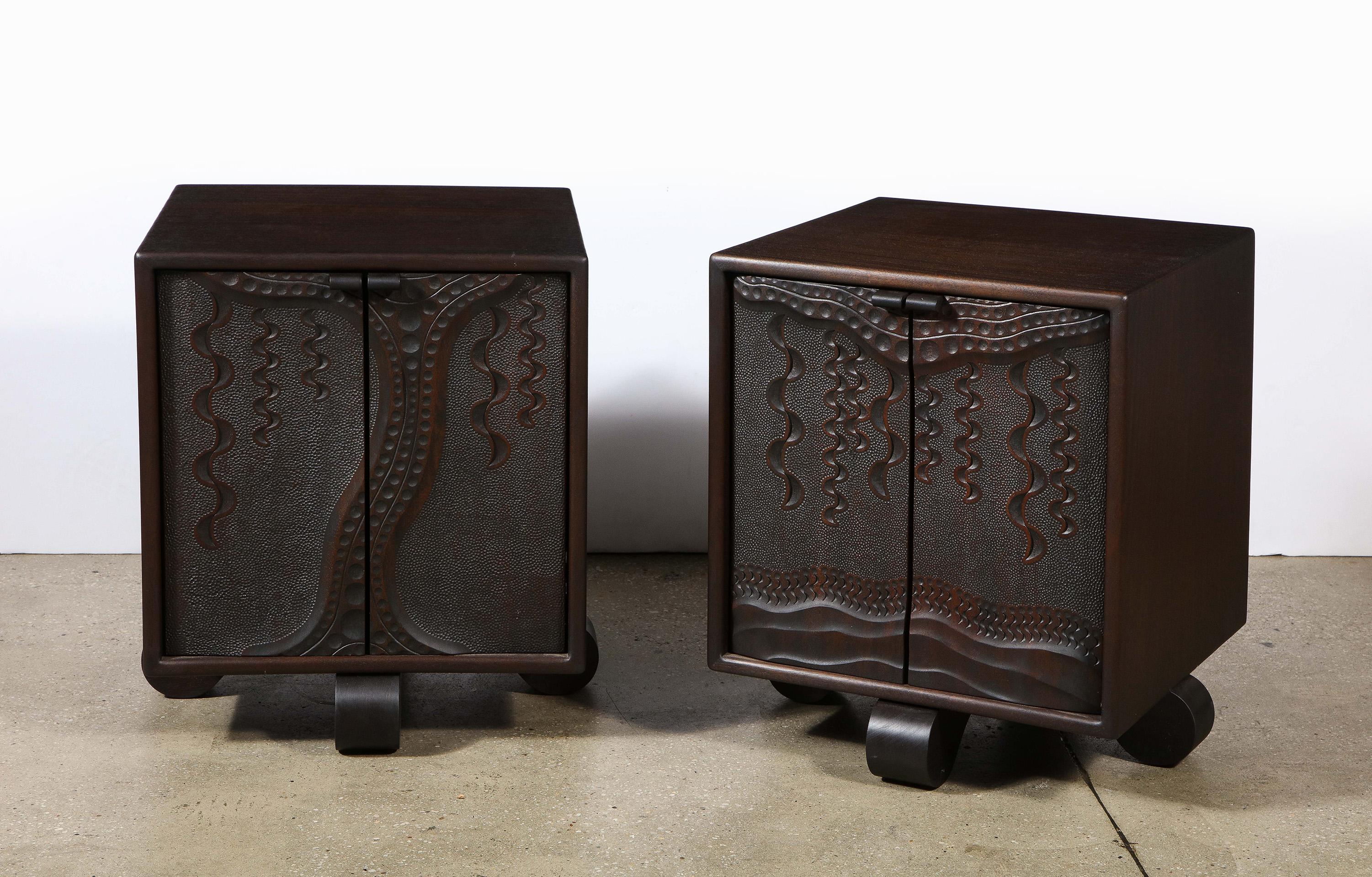 Mahogany, the square cabinets having two doors with intricately incised carving opening to reveal shelves. The whole on a raised foot.

 