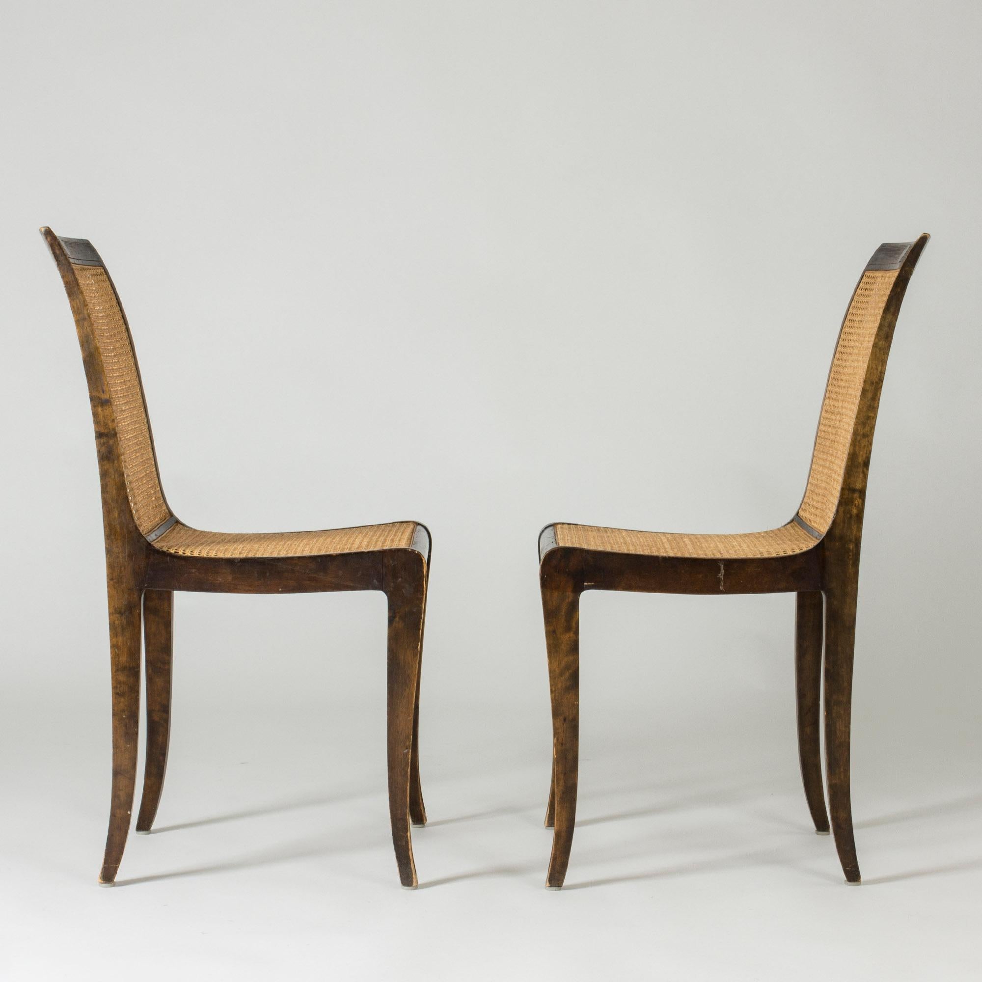 Pair of beautiful side chairs by Carl Malmsten. Made from stained wood with rattan backs, contrasting elegantly in color. Lovely, flowing lines, light expression.