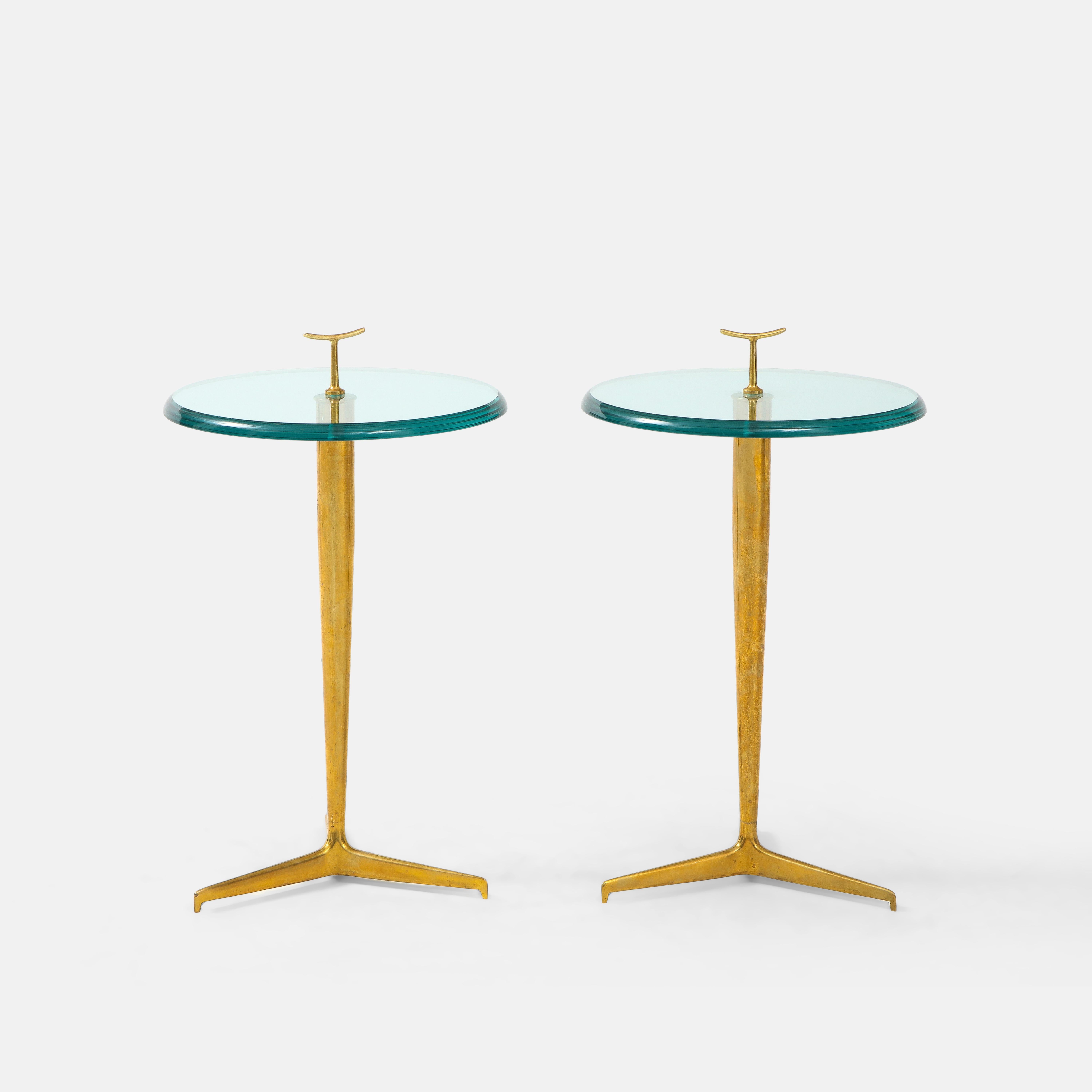 Contemporary custom pair of chic side, end, or drinks tables in thick beveled glass with small brass handle detail on patinated brass tripod base, Italy, 2023. These modernist side tables are beautifully constructed with thick lens cut polished