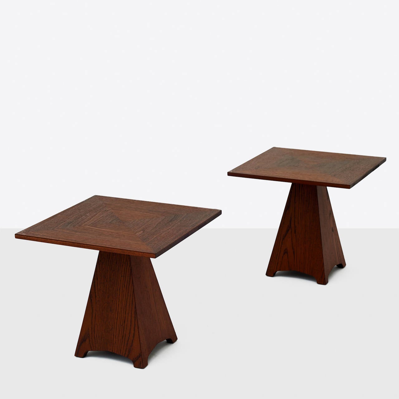 A pair of wooden side tables by Harvey Probber. Features a square tabletop with a trapezoidal base. Manufacturer's mark to underside 