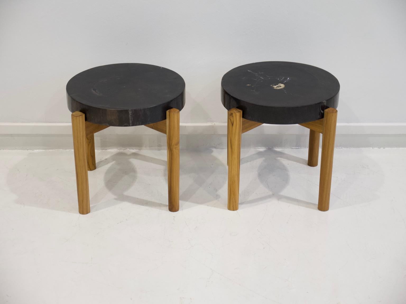 Two round side or end tables with dark petrified wood top. Feet made of light color wood. Measurements of each: height 41 cm, diameter 40 cm.