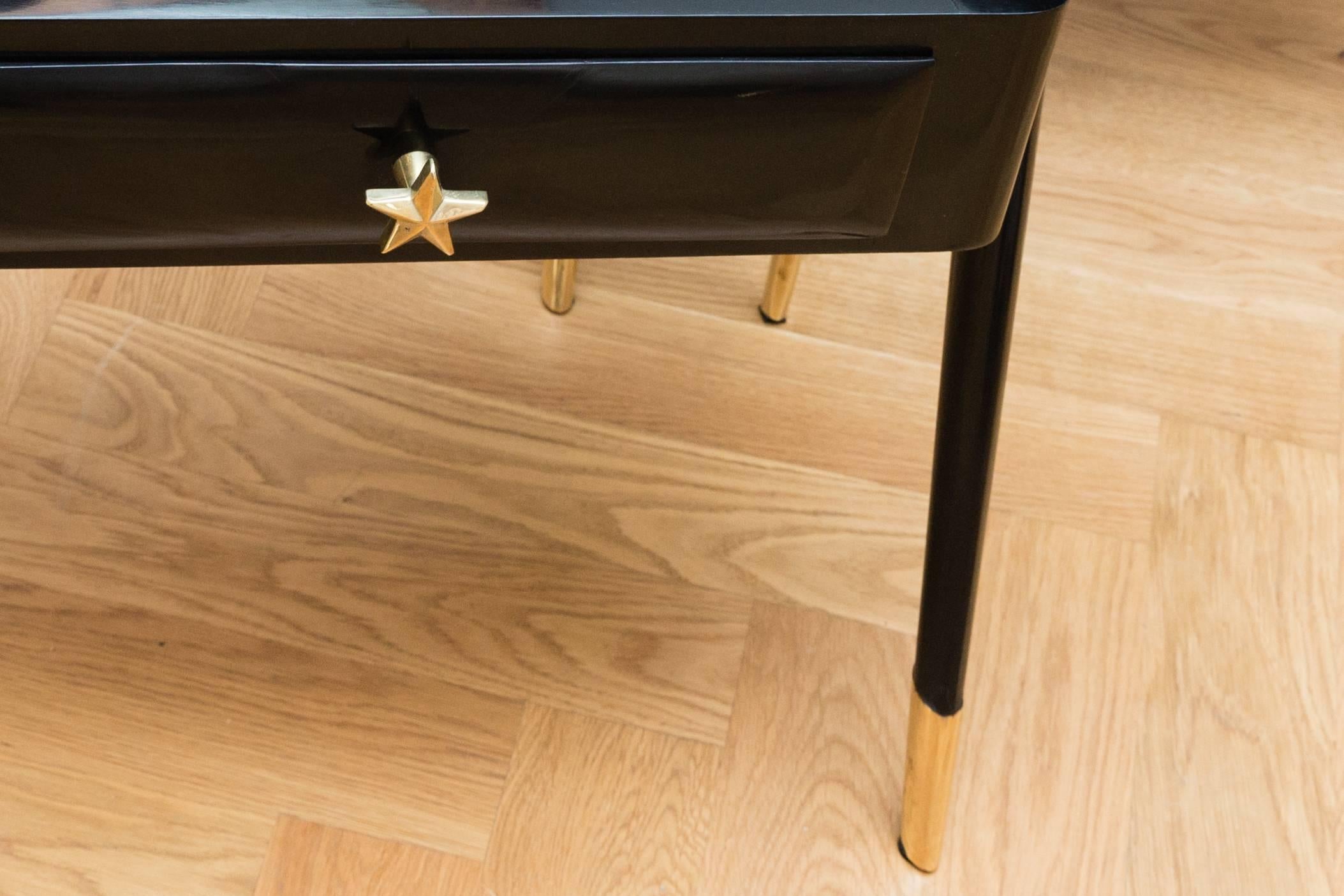 Elegant pair of side tables, Italy, circa 1950. Black shellac polished wood, organic shaped legs, solid polished brass legs, each have a glass shelf fixed with polished brass brackets and a drawer with a solid polished brass star handle. Each of the