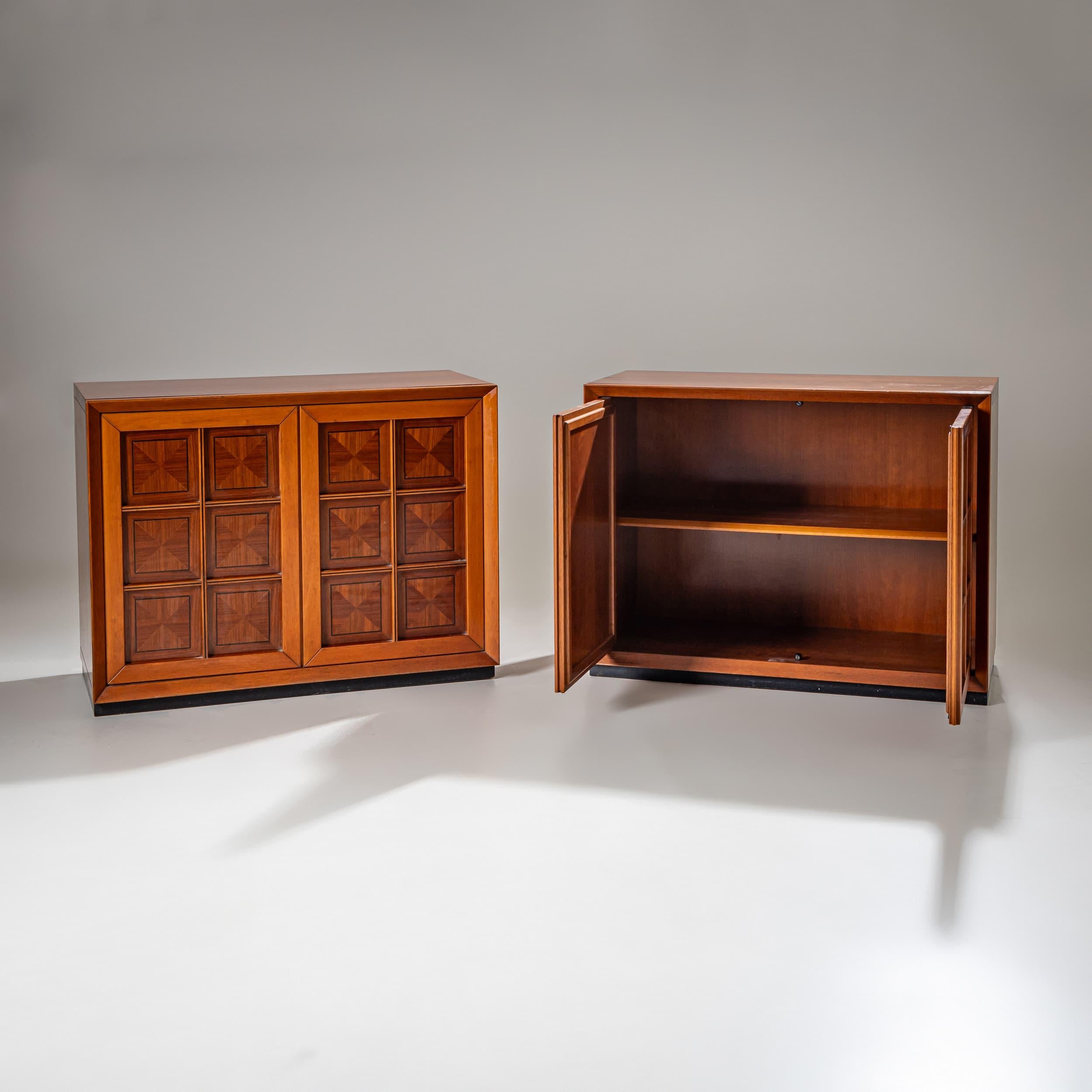 A striking pair of sideboards from the 1970s featuring the signature geometric design of Mobili i Caccia alla Volpe. The doors are adorned with square inlays in contrasting wood tones, creating a textured, dimensional effect. Beveled door frames