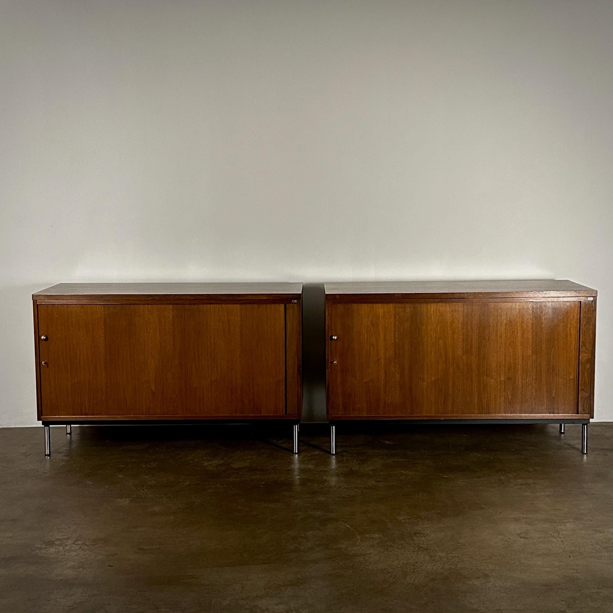Pair of Dutch 1970s walnut wood sideboards or large nightstands featuring sliding doors set on slim chrome legs. These pieces embody sophisticated mid-century elegance with a grounded yet lightweight feel, offering versatility and a streamlined