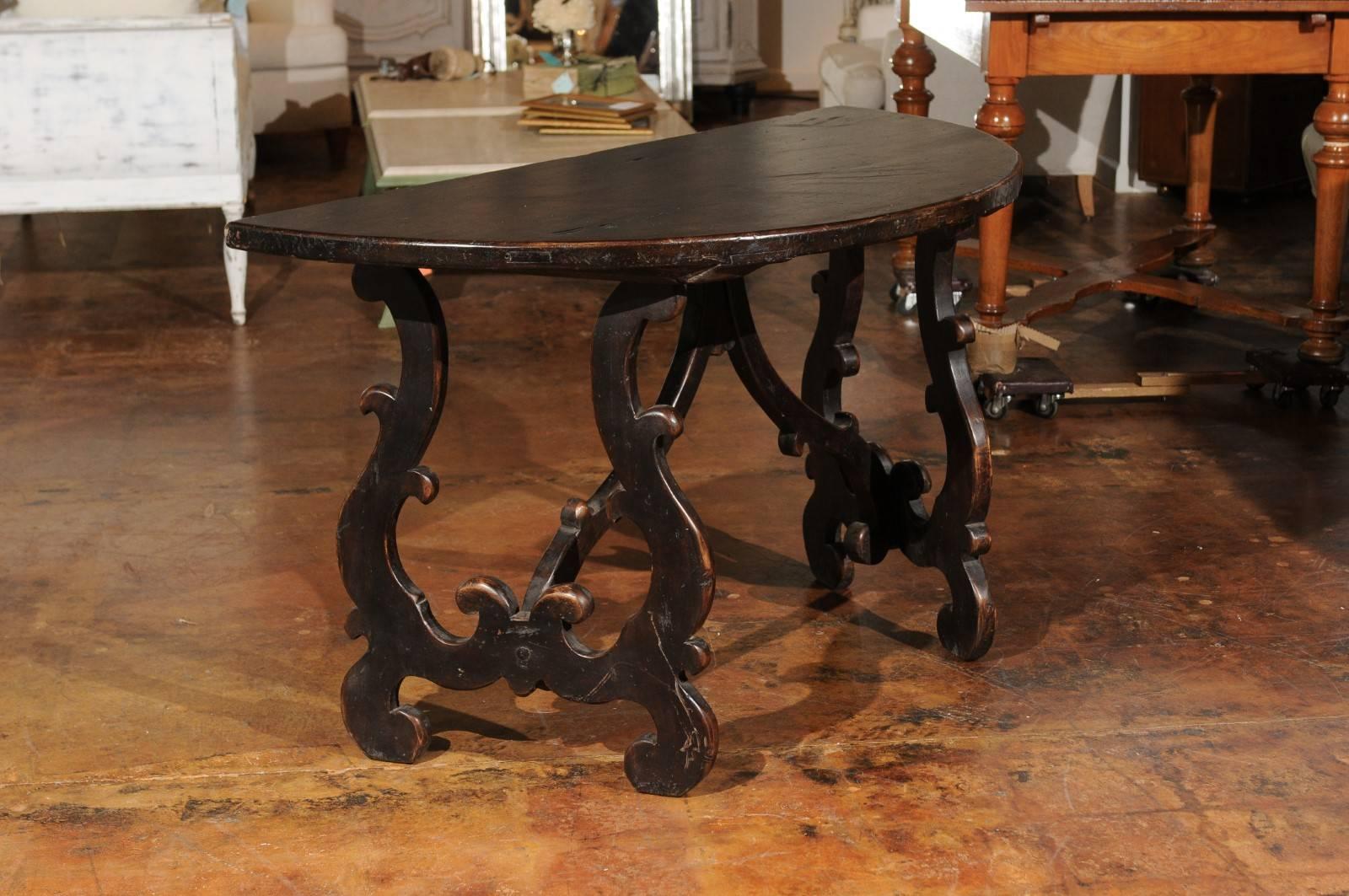A pair of Italian Sienese Baroque style walnut demi-lune consoles tables with lyre-shaped legs from the late 18th century. Born in the Tuscan city of Siena, this pair of Italian demilune was found in a villa. Each table features a semi-circular top