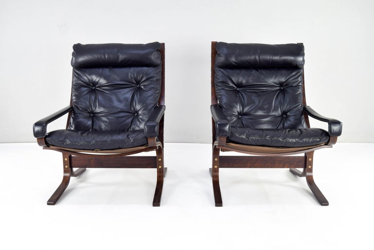 Pair of Siesta armchairs and a ottoman, designed by Ingmar Relling (1965) and manufactured by Westnoffa in Norway in the early 1970s.
High back edition with headrest and armrests. Black leather upholstery in very good condition.
Set with original