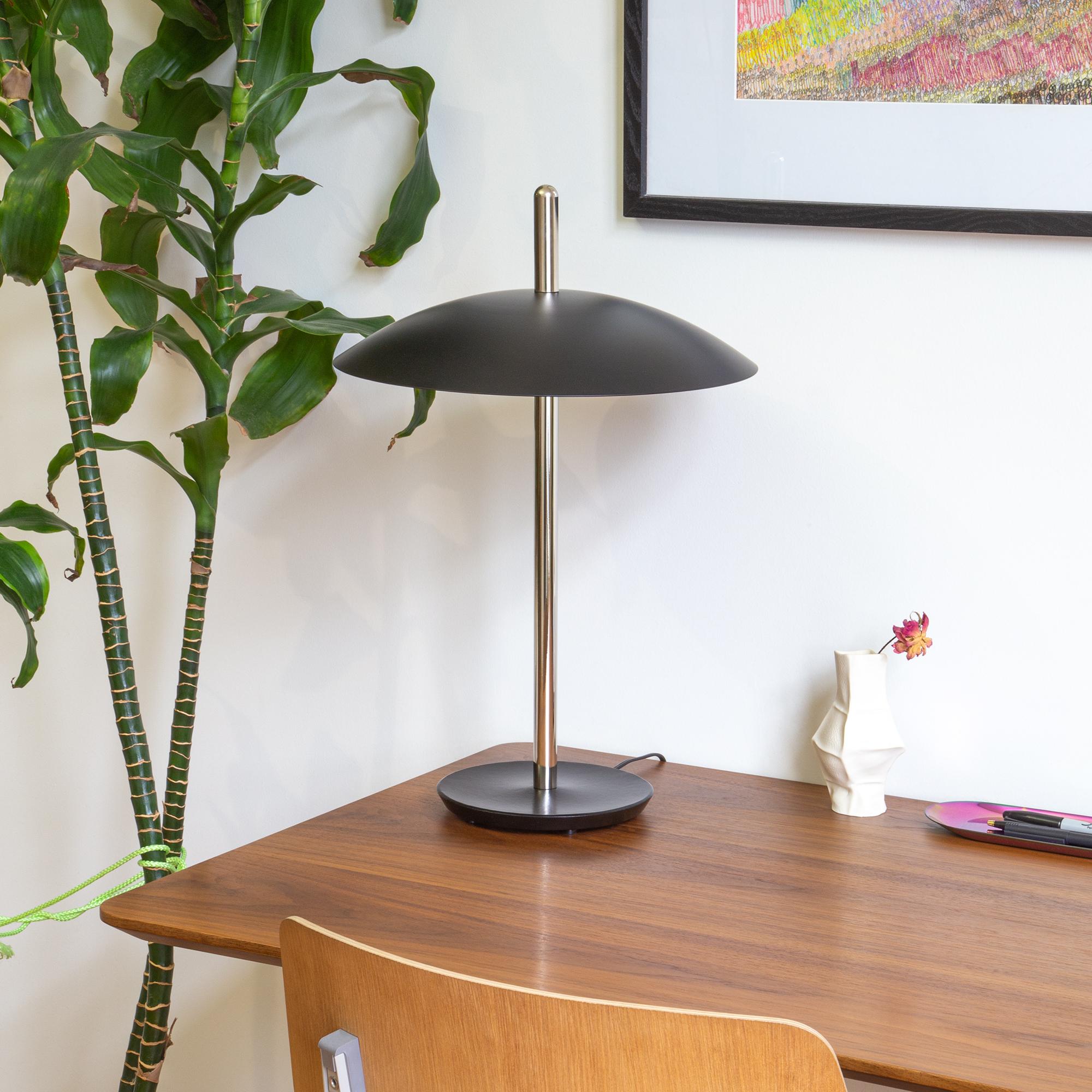 La lámpara de mesa Señal es familiar, pero futurista. Desde debajo de su pantalla de metal hilado, los LED proyectan un cálido y acogedor resplandor sobre un tallo central pulido apoyado en una base de hierro fundido. Con su forma refinada y sus