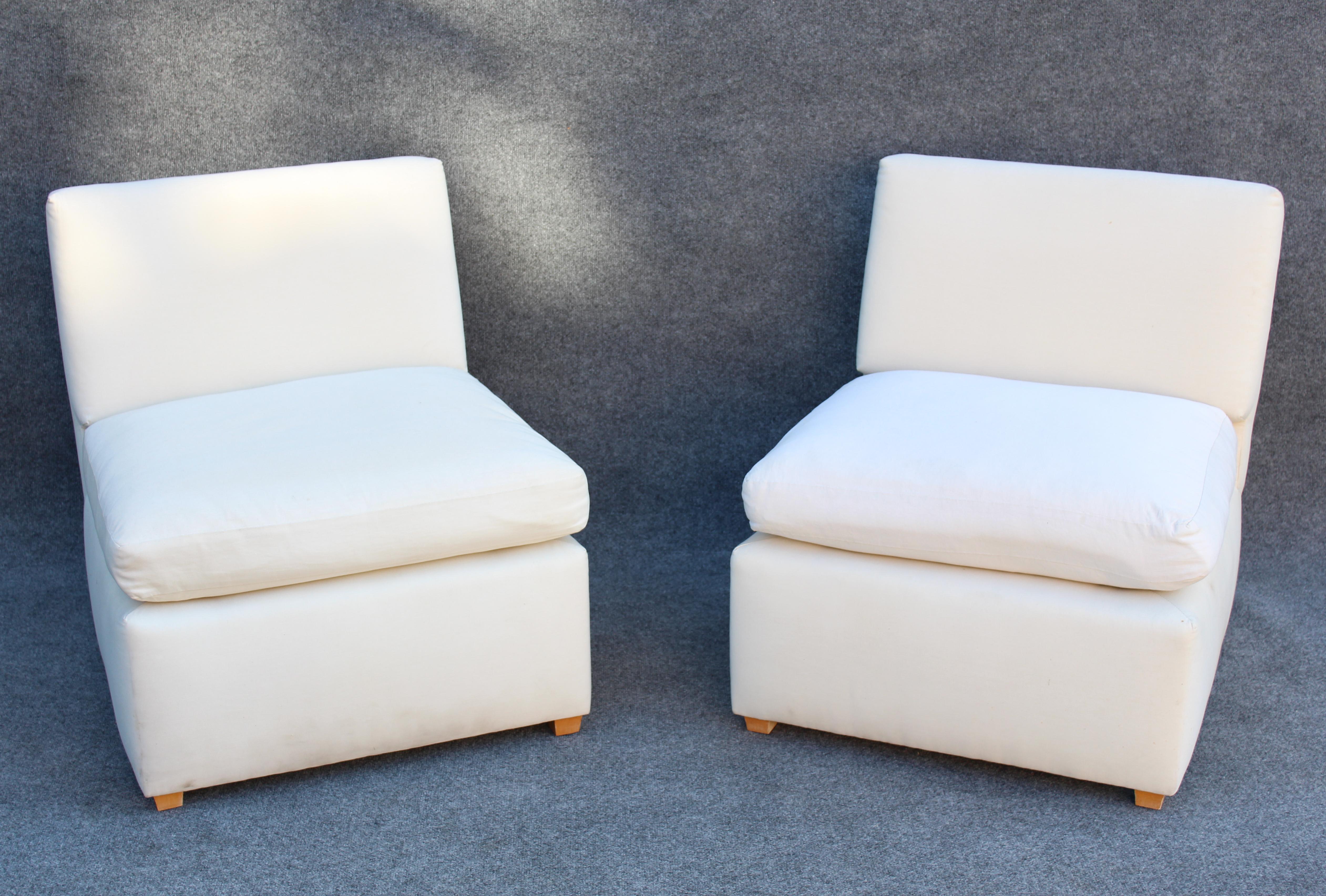 Designed by Billy Baldwin in the 1980s, these rarely signed slipper style lounge chairs feature an elegant and simplistic design language with a crease where the seat meets the back. Upholstered in a pleasant white, each chair has a soft cushion