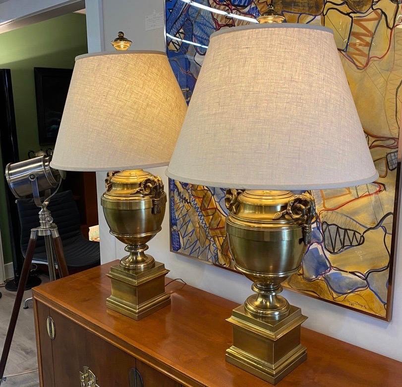 Stunning pair of large vintage brass urn form lamps with carved handles.  Comes with shades. 
