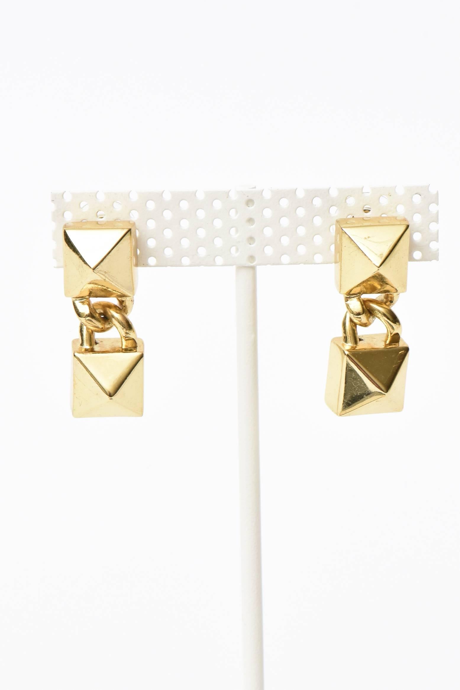 These dynamic pair of signed Fallon pierced dangle drop earrings are sculptural and dimensional. Inverted raised sculptural forms in a raised pattern that is almost hard to see in these photos make up the shape. They are gold plated and look