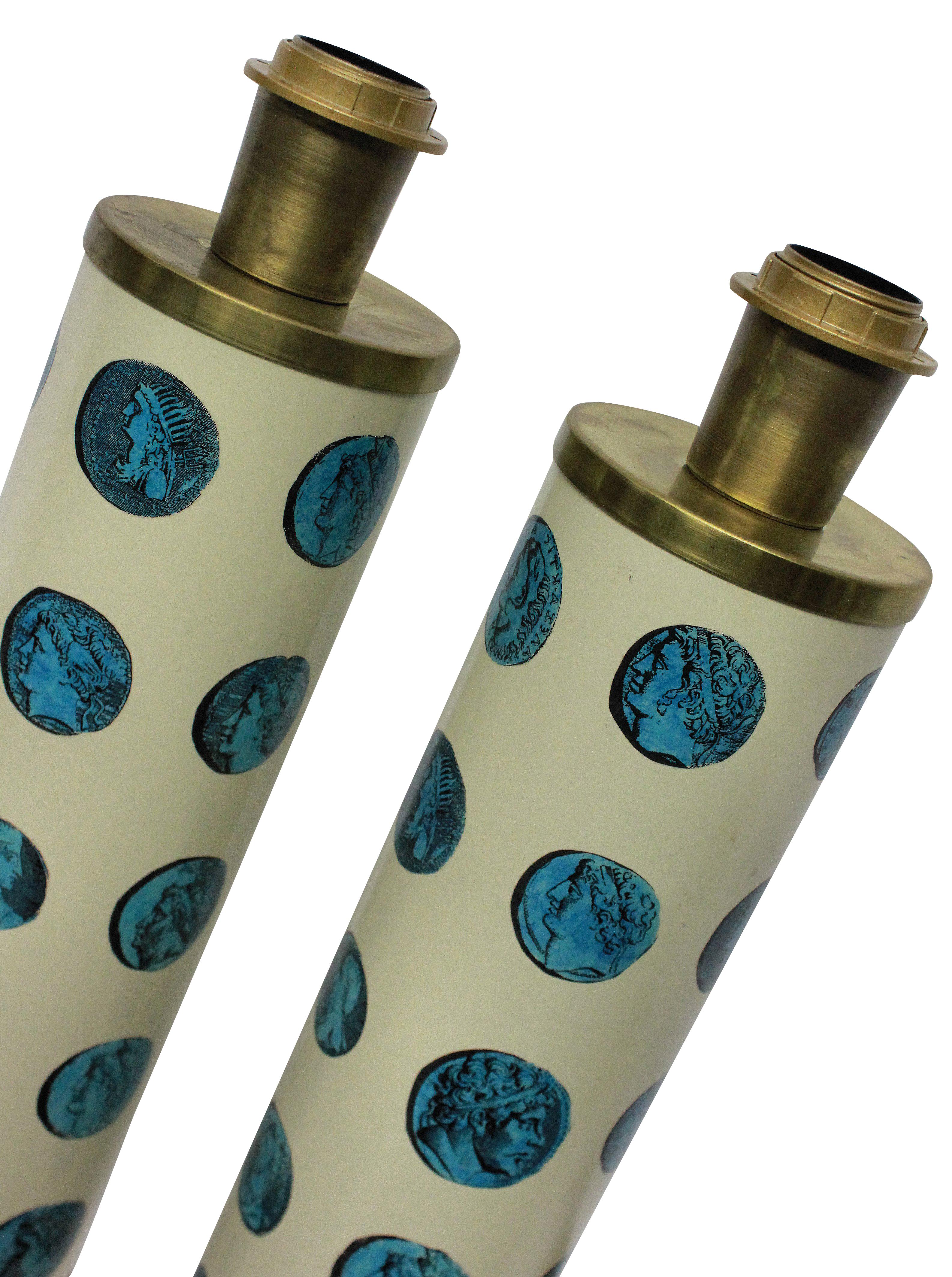 A pair of Fornasetti table lamps in enamel and brass, depicting ancient Roman coins in pale blue on an ivory background.