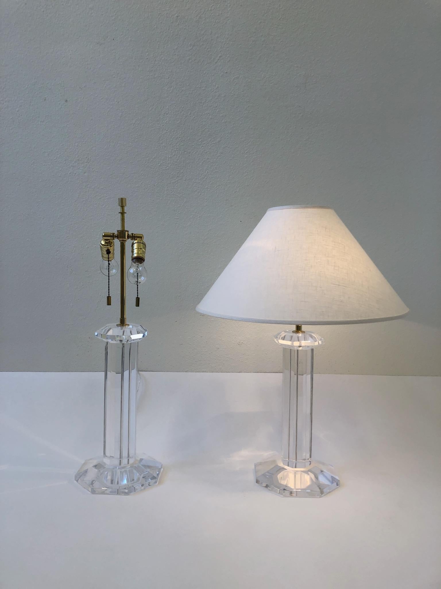 A glamorous pair of octagonal shape, clear lucite and polish brass table lamps. Design by Karl Springer in the 1980s. The lamps have been newly professionally polished and rewired with new vanilla linen shades.
The lamps have minor crazing on the