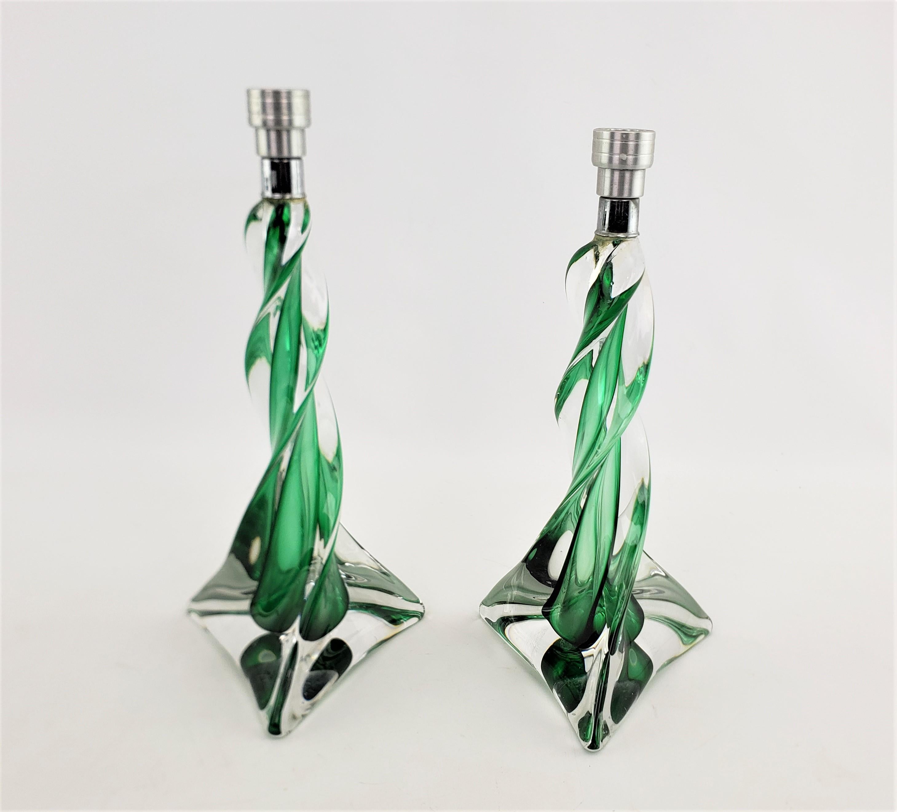 This pair of graduated sculptural crystal candlesticks were made by the renowned St. Louis Crystal factory of France in approximately 1965 in the period Mid-Century Modern style. The candlesticks are done with clear crystal formed in an stylized